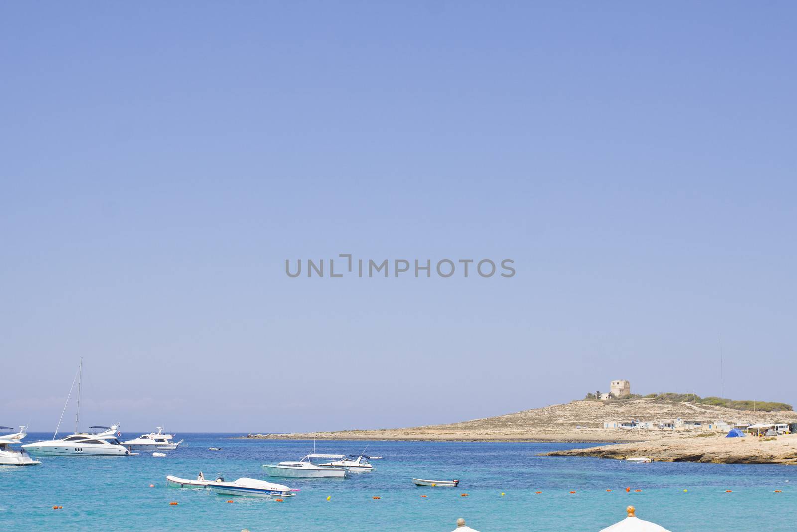 Coastline in Malta with blue sea, blue sky and power boats. Space for text