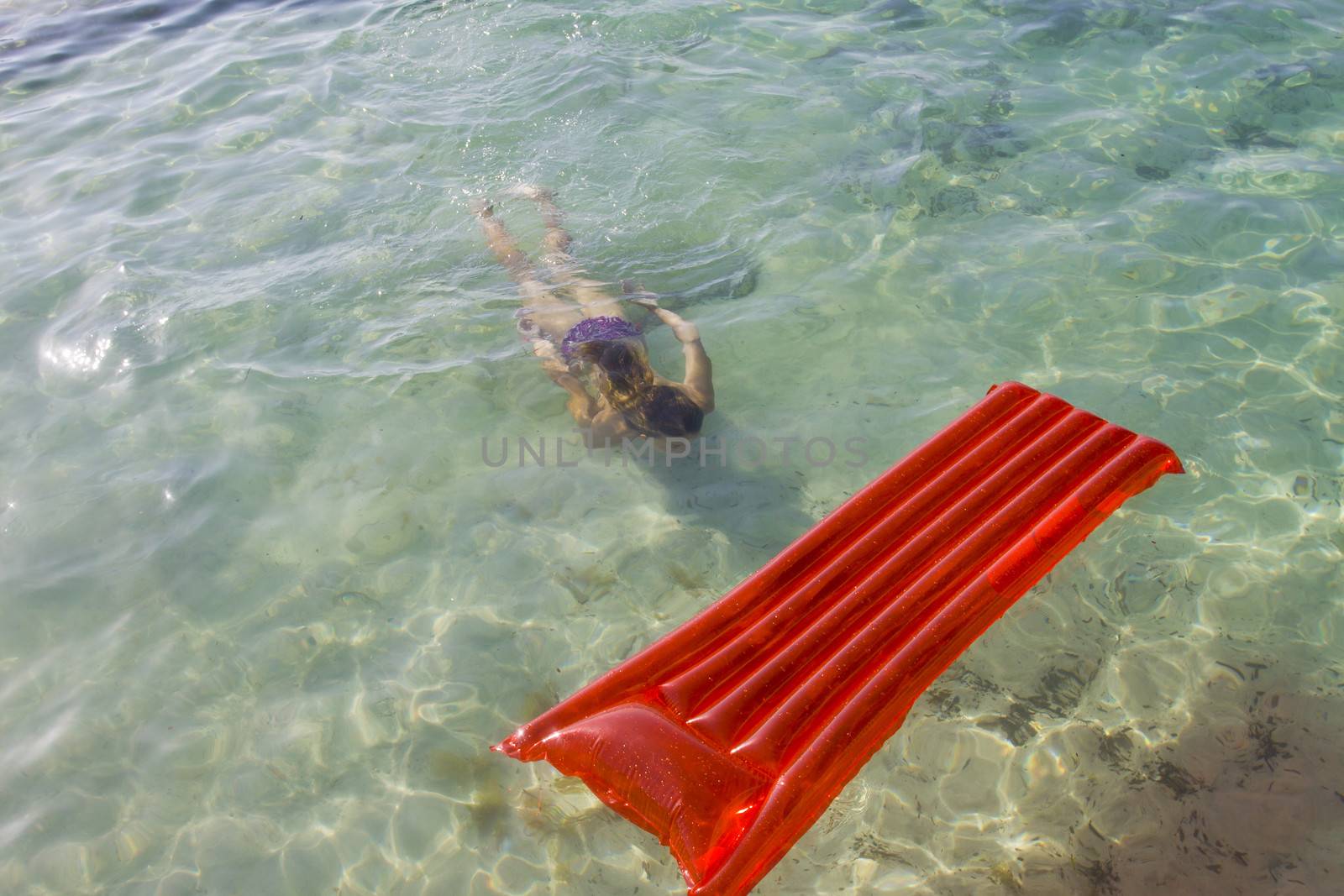 A teenager free diving towards an inflatable air mattress