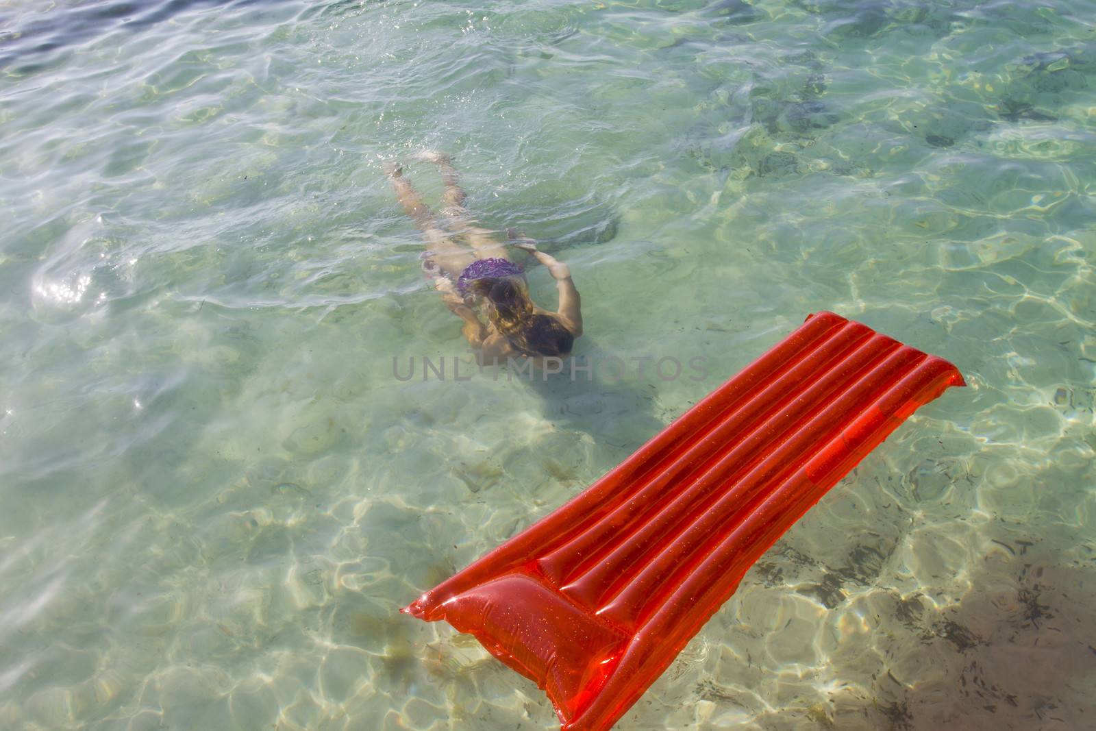 Woman diving under water towards a lilo by annems