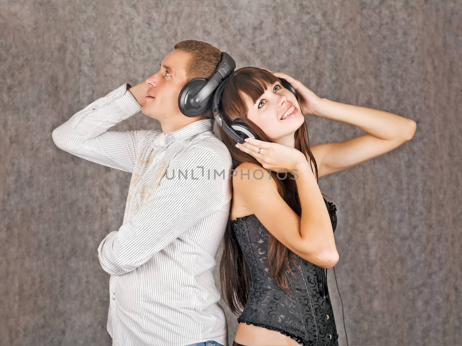 A girl and a boy, smiling happily, listening to music via headphones