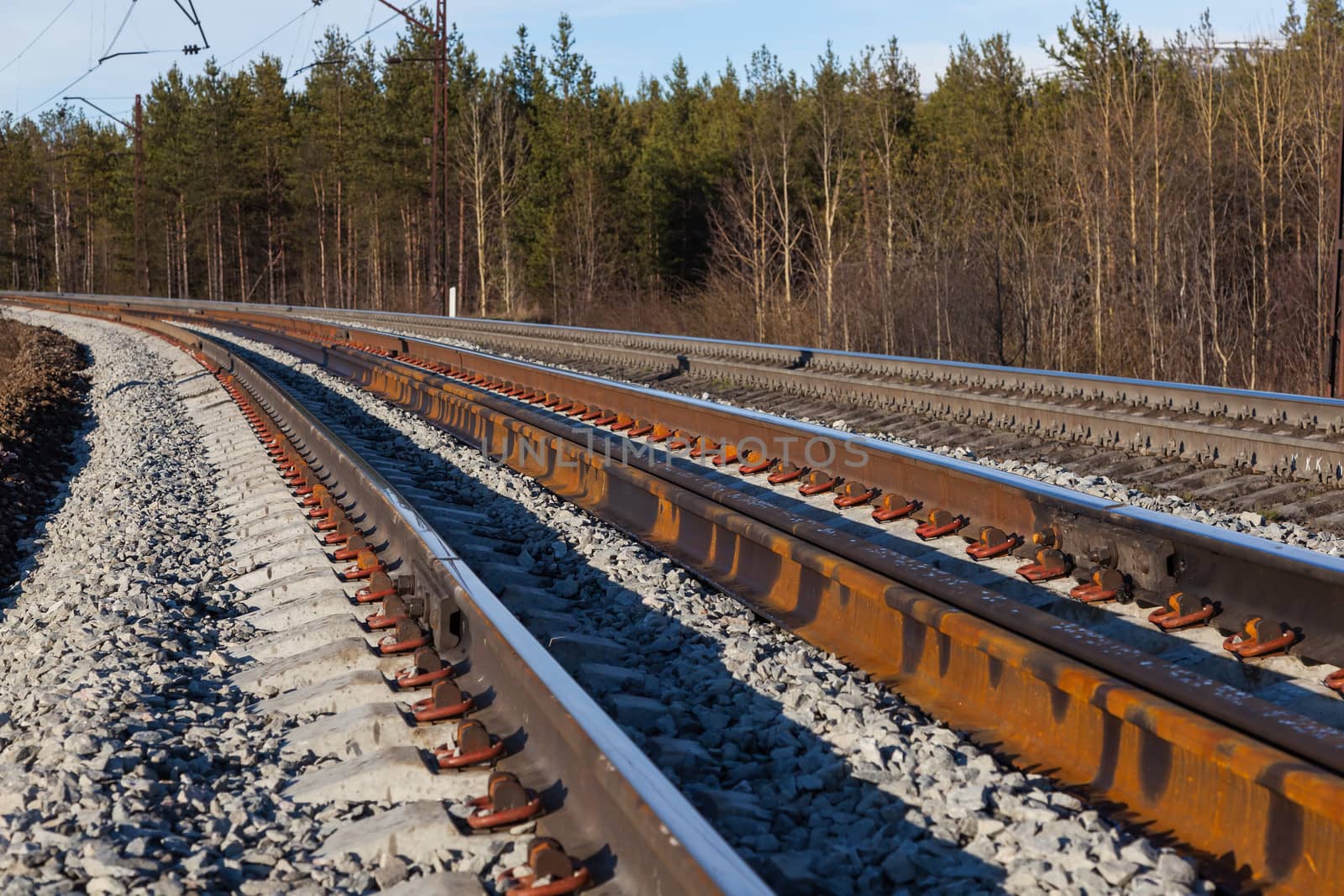 Railway in the forest makes a smooth turn . Against the background of the setting sun