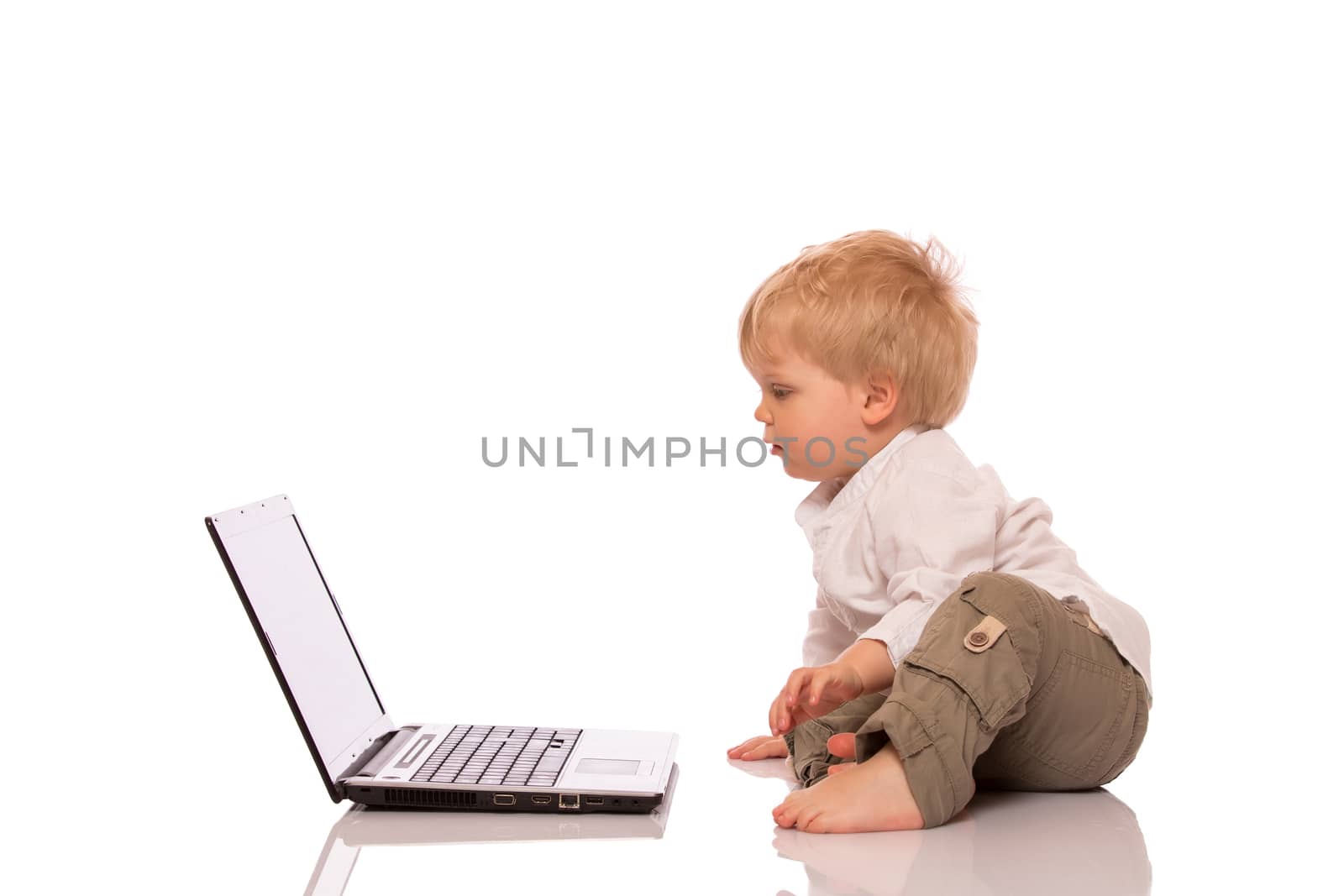 Young boy looking at a laptop on a stool. Isolated on white background