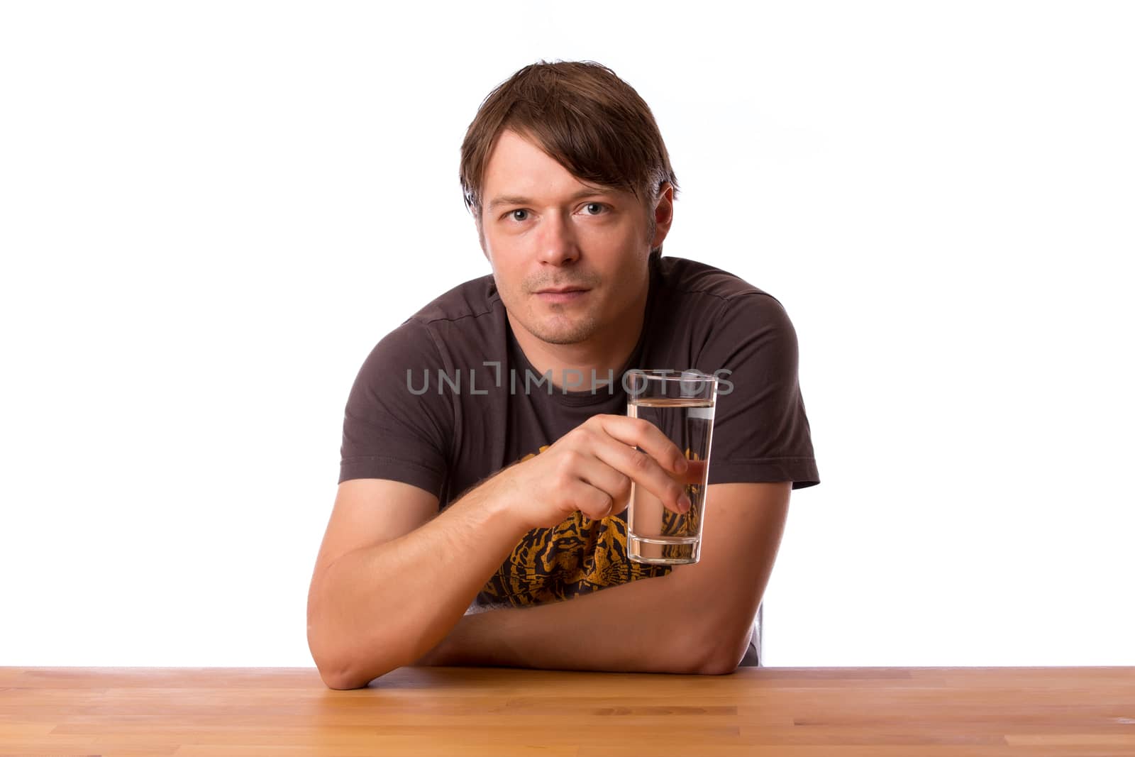 Man sitting at a wooden table with a glass of water. Isolated on a white background