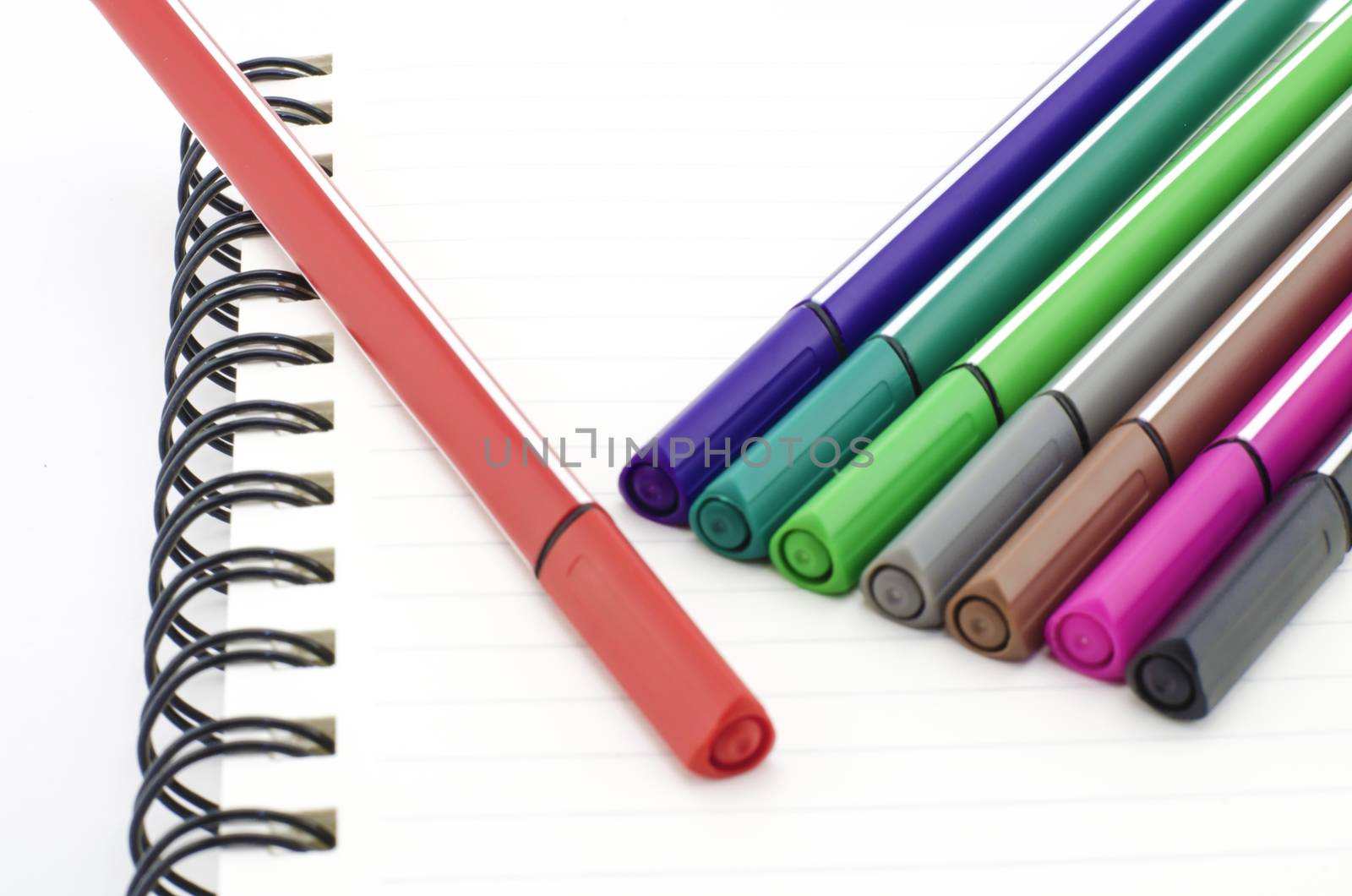colorful pen with notebook isolated on white by ammza12