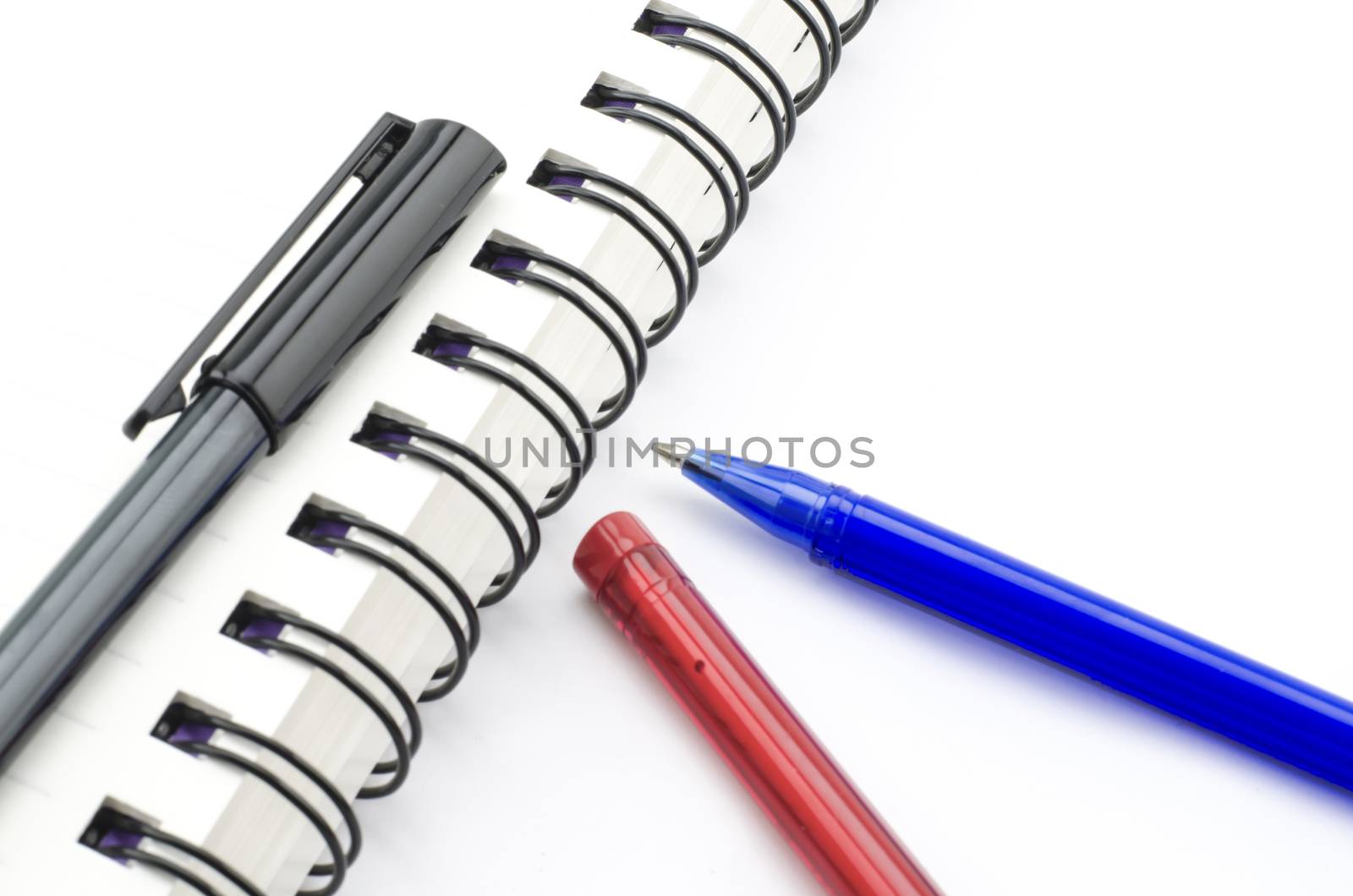 black red and blue pen with notebook isolated on white by ammza12