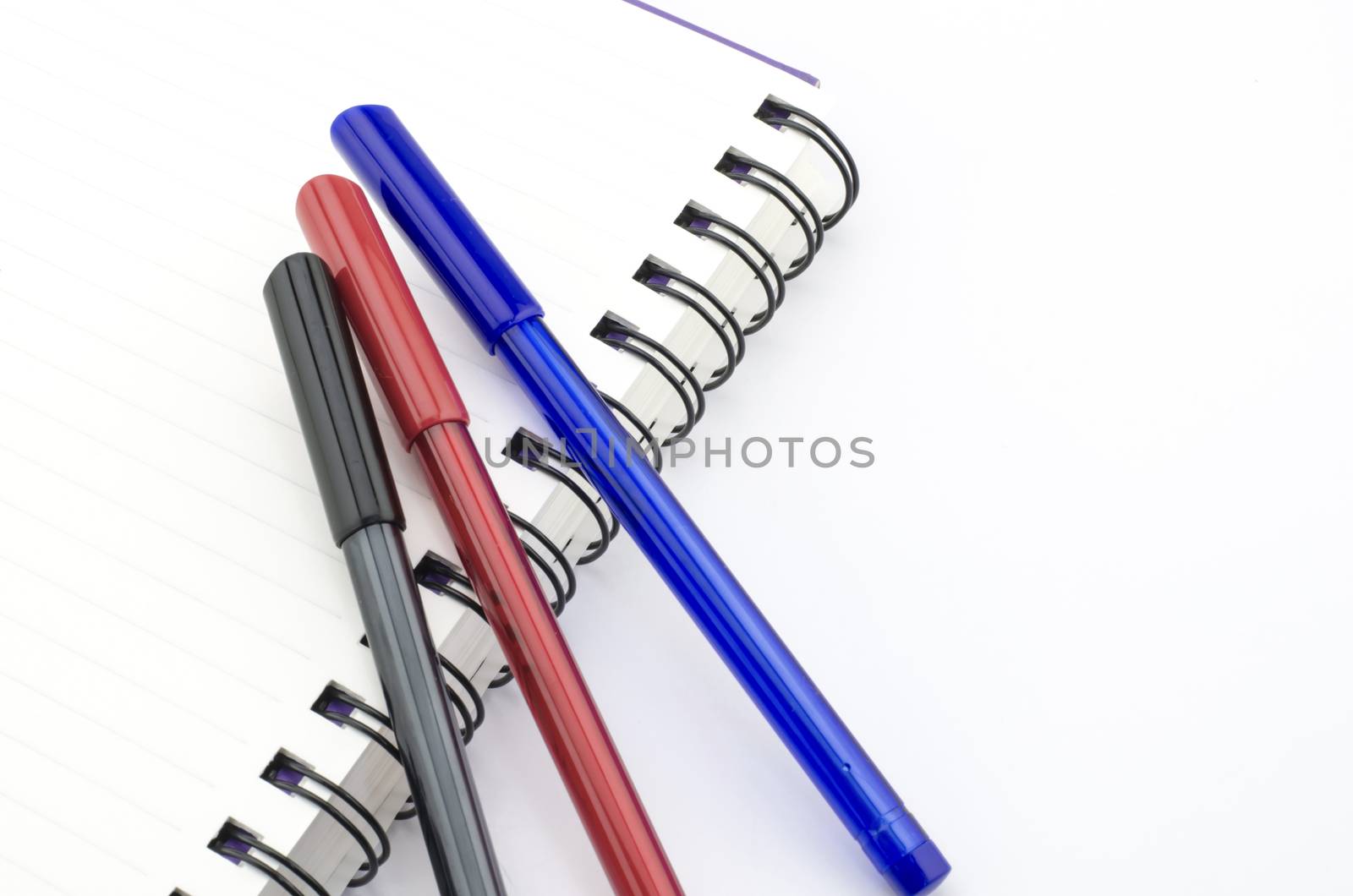 black red and blue pen with notebook isolated on white by ammza12