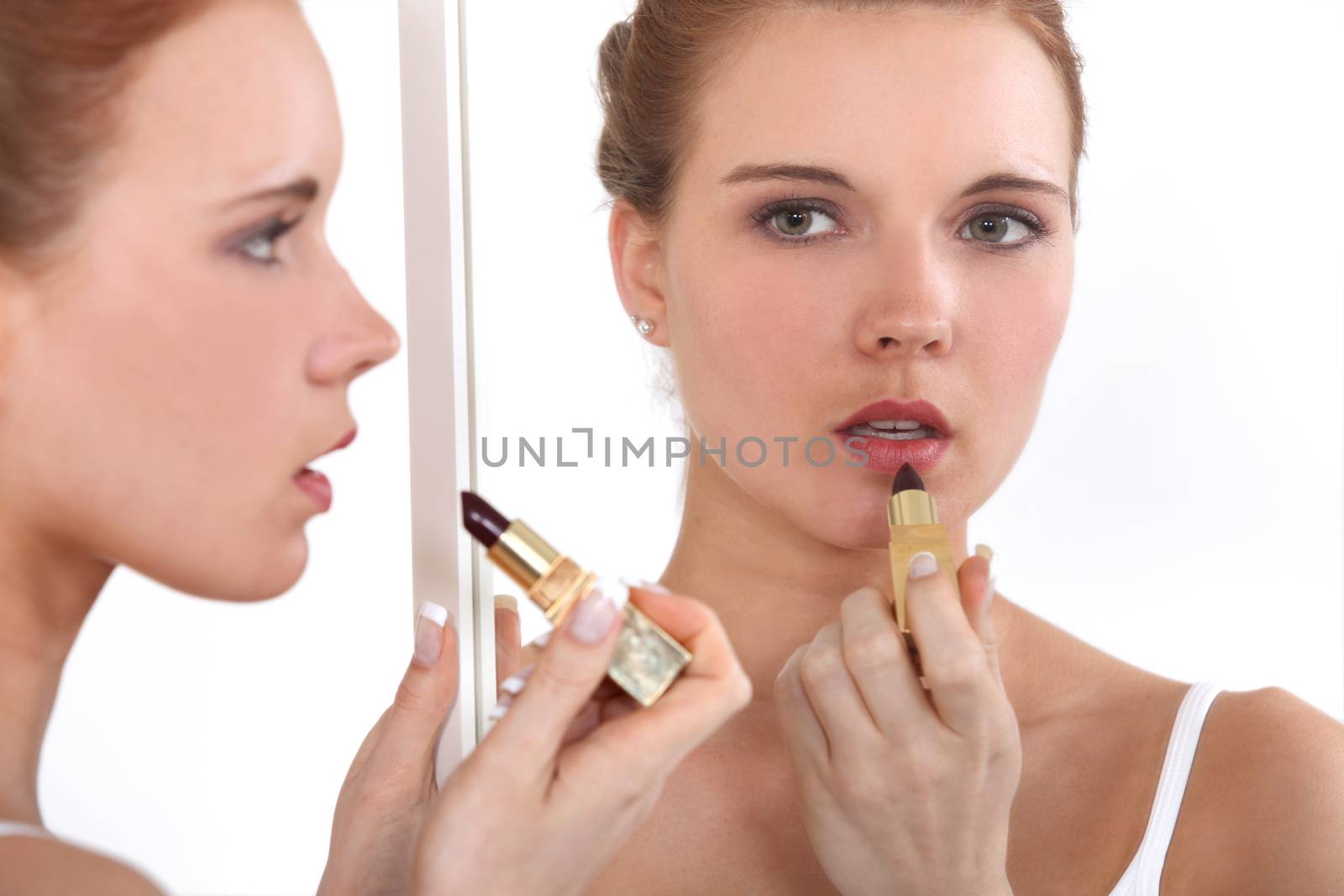 Woman applying lipstick in mirror