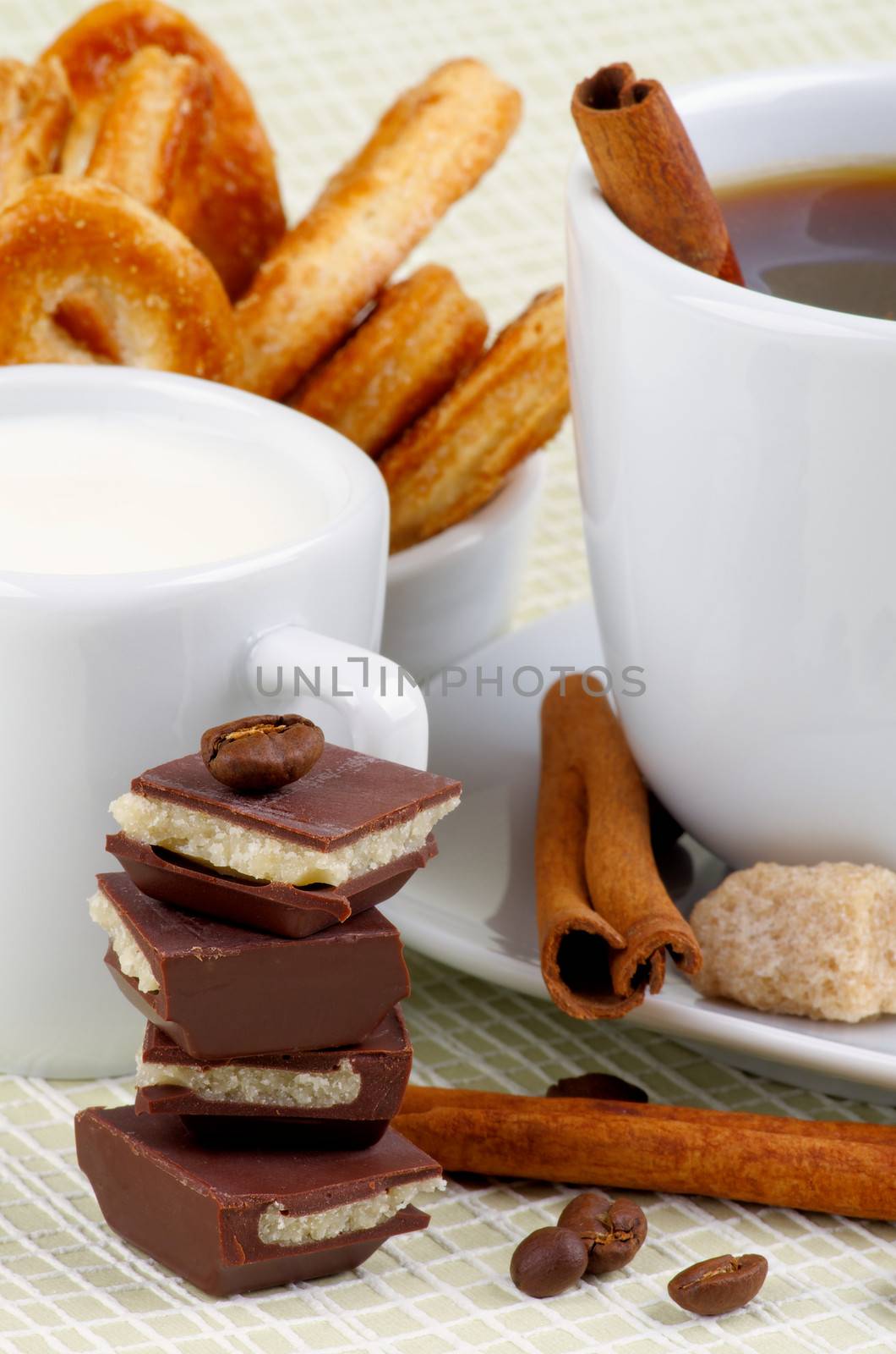 Arrangement of Coffee Cup, Milk and Puff Pastry with Chocolate, Sugar and Cinnamon Sticks closeup