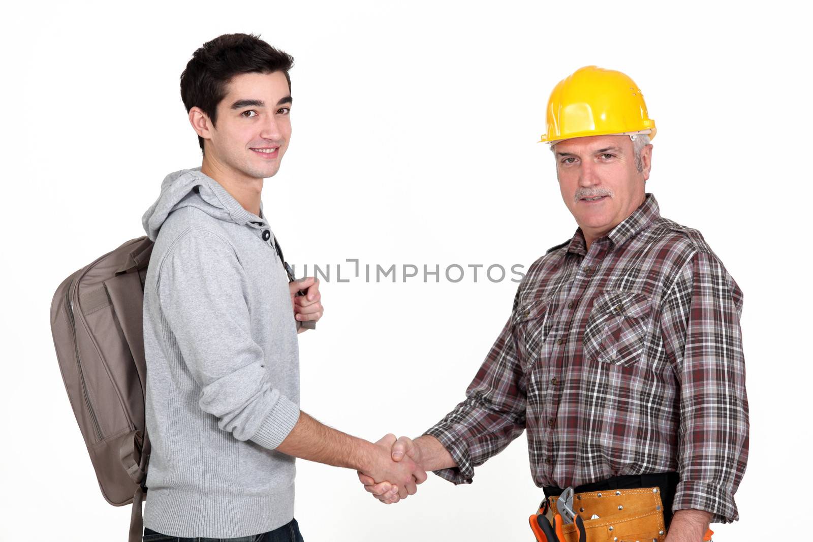 Construction worker shaking hands with a college student by phovoir