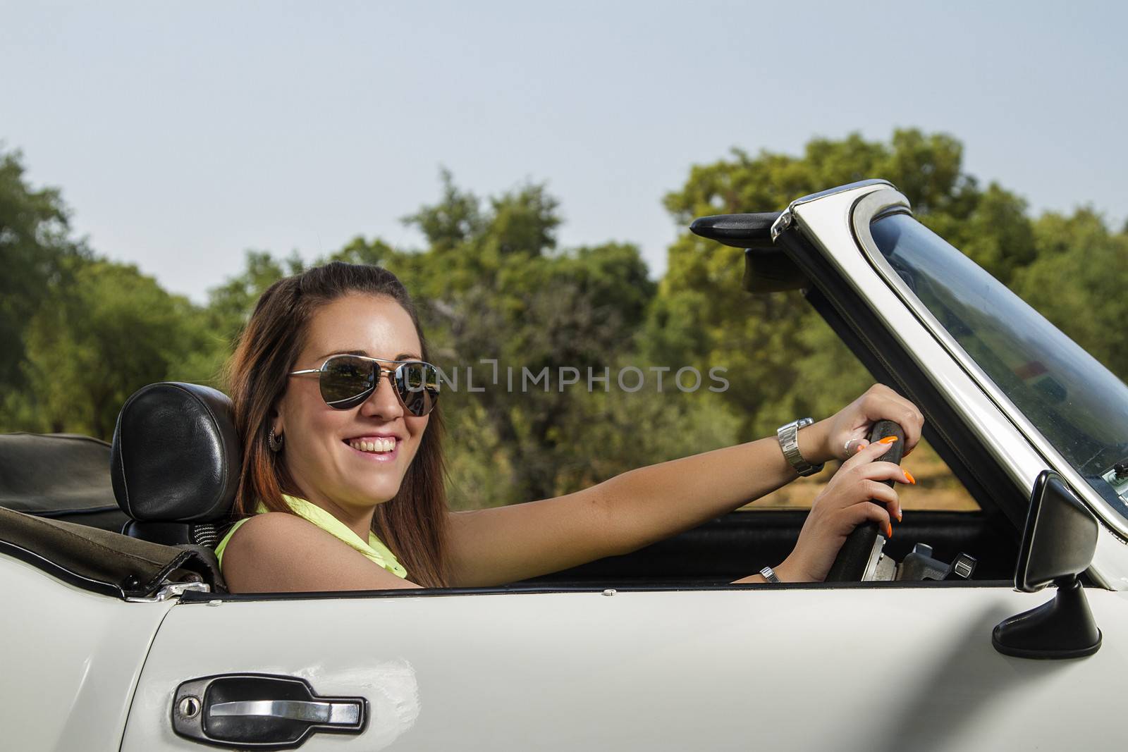 View of a beautiful woman posing on a white convertible car.