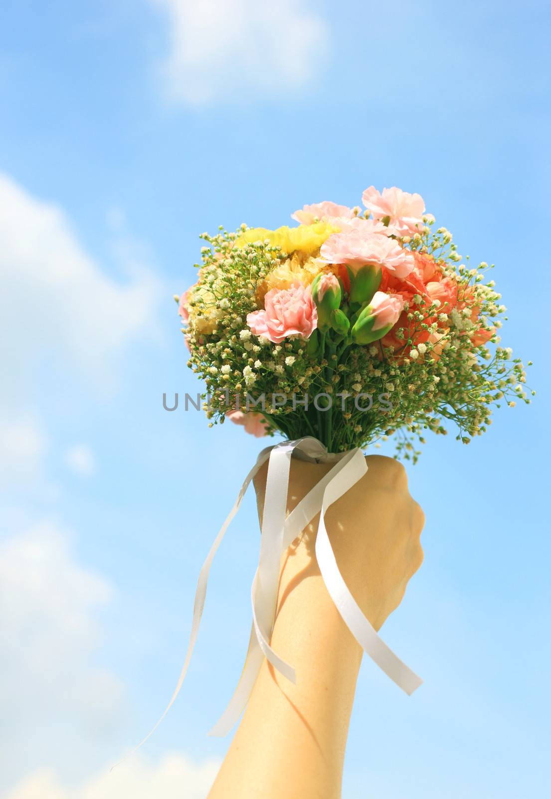 Bouquet of flower in hand and blue sky 