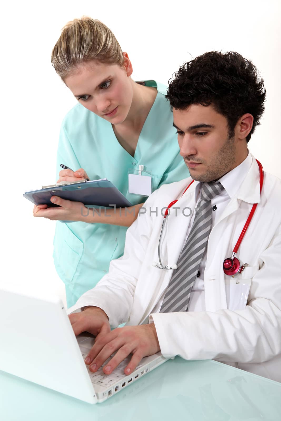 A nurse and a doctor checking their laptop.