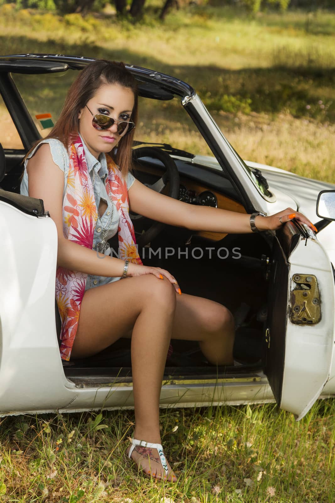 View of a beautiful woman posing on a white convertible car.