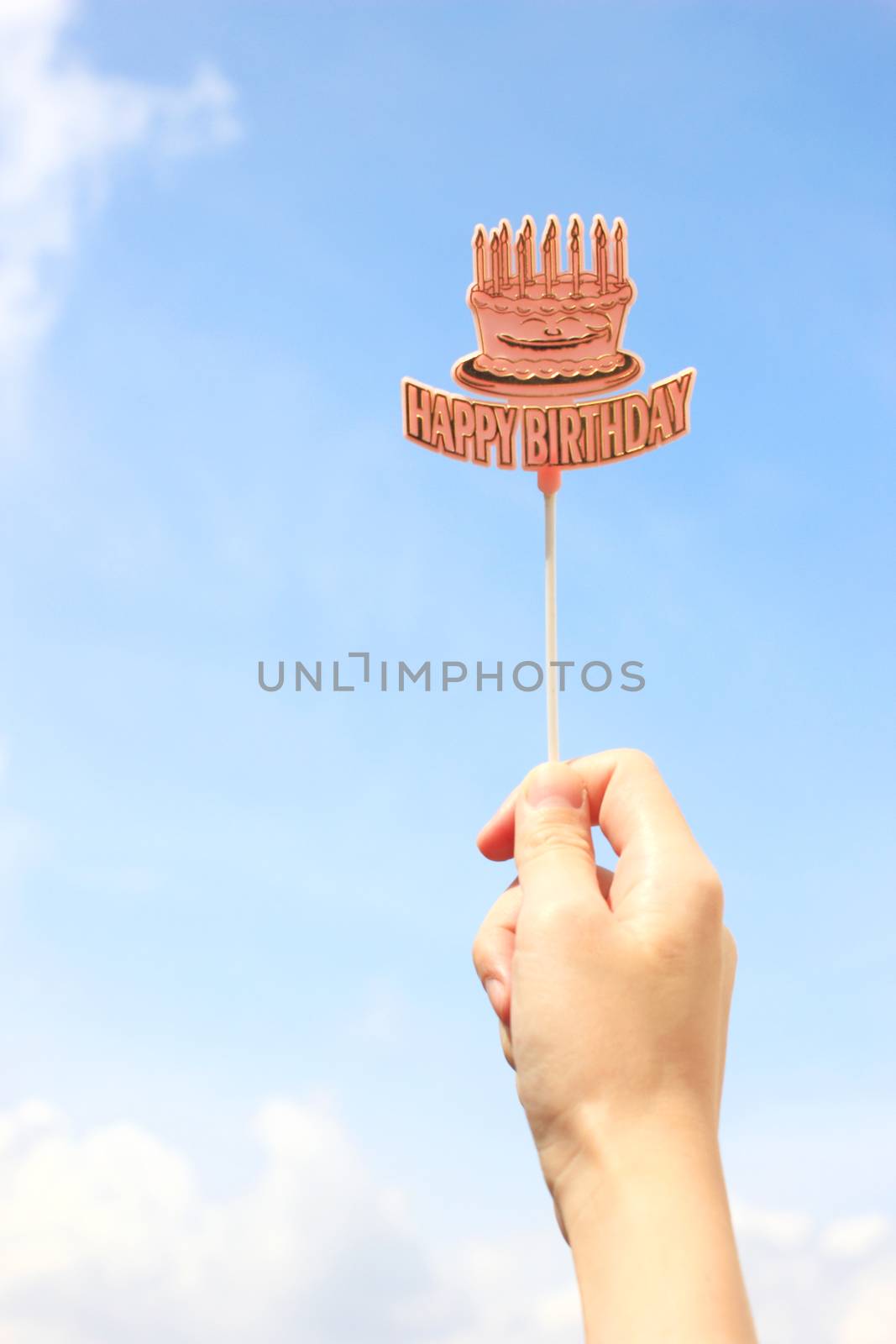 Hand holding happy birthday tag with blue sky