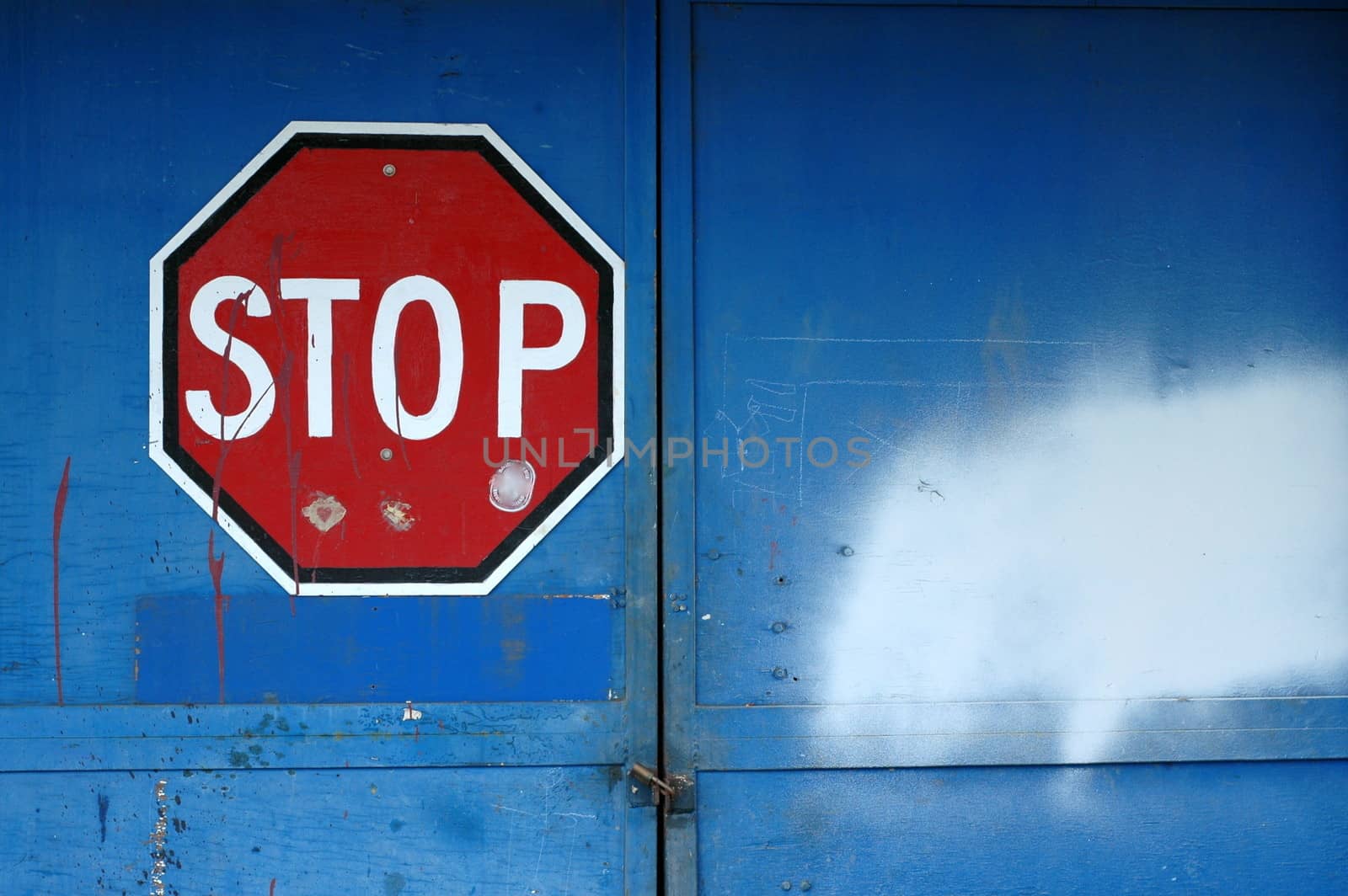 A Red Stop Sign on a Locked Blue Door of an Abandoned Warehouse with Copy Space
