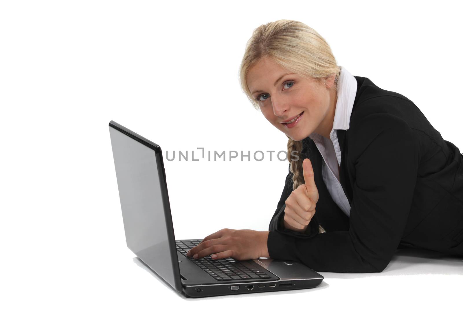 A businesswoman lying on the floor with her laptop.
