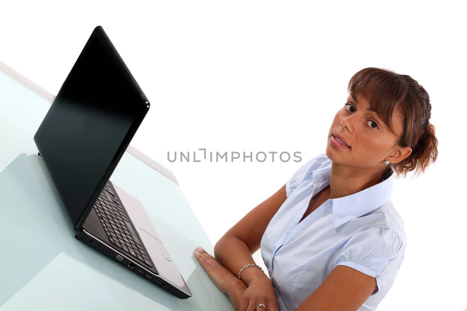 Woman using a laptop at a desk by phovoir