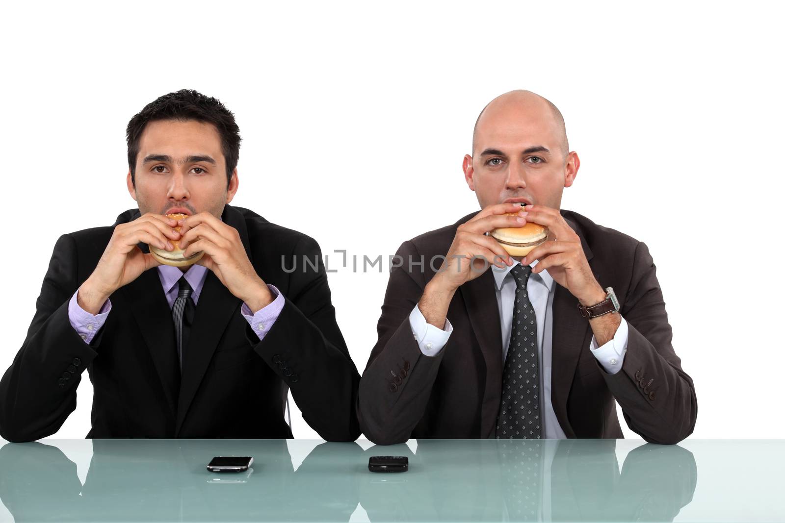 Two businessmen enjoying a burger. by phovoir