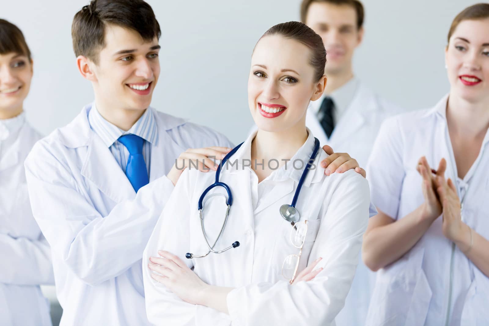 Attractive female doctor in uniform congratulated by colleagues