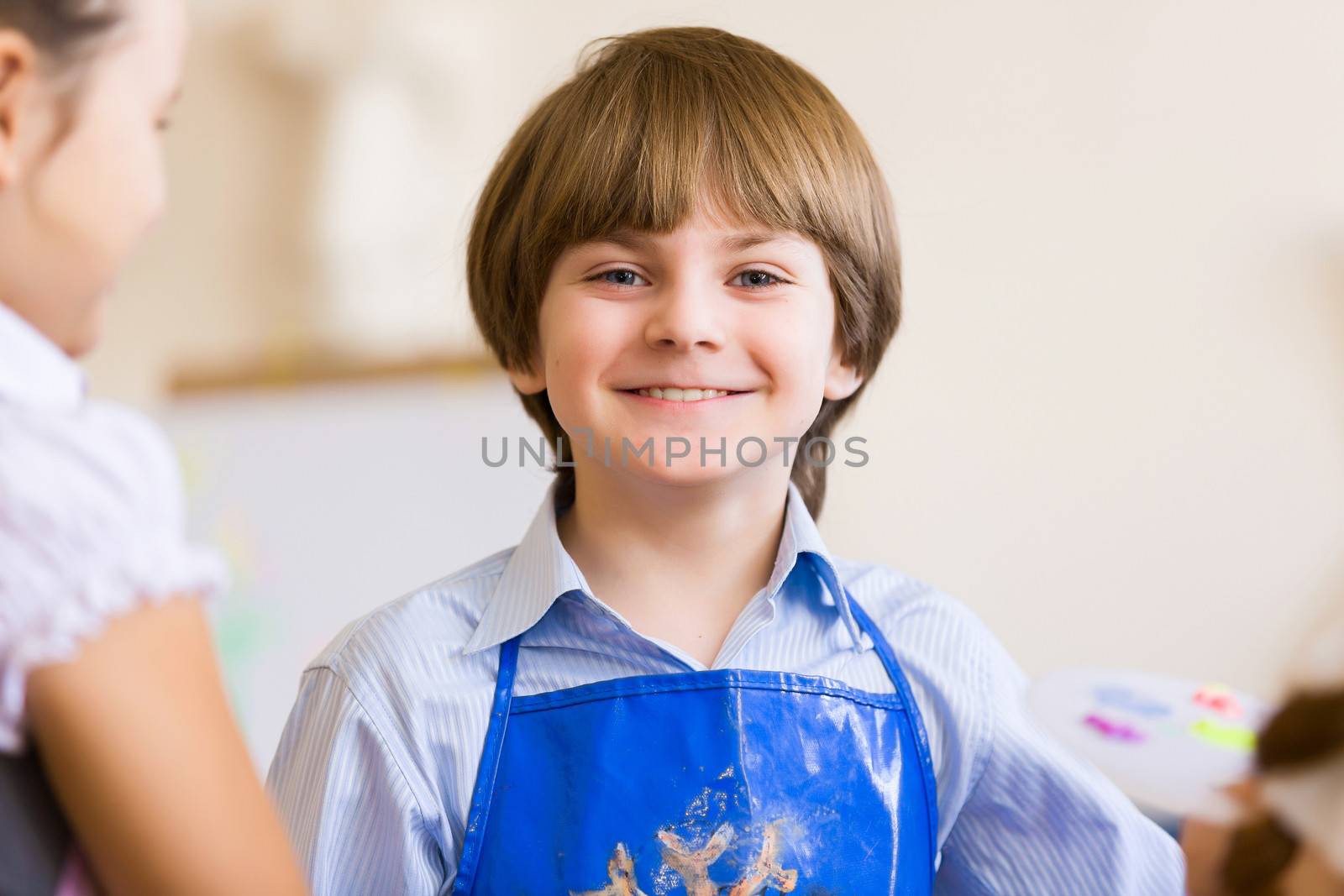 Image of little cute boy painting pictures at kindergarten
