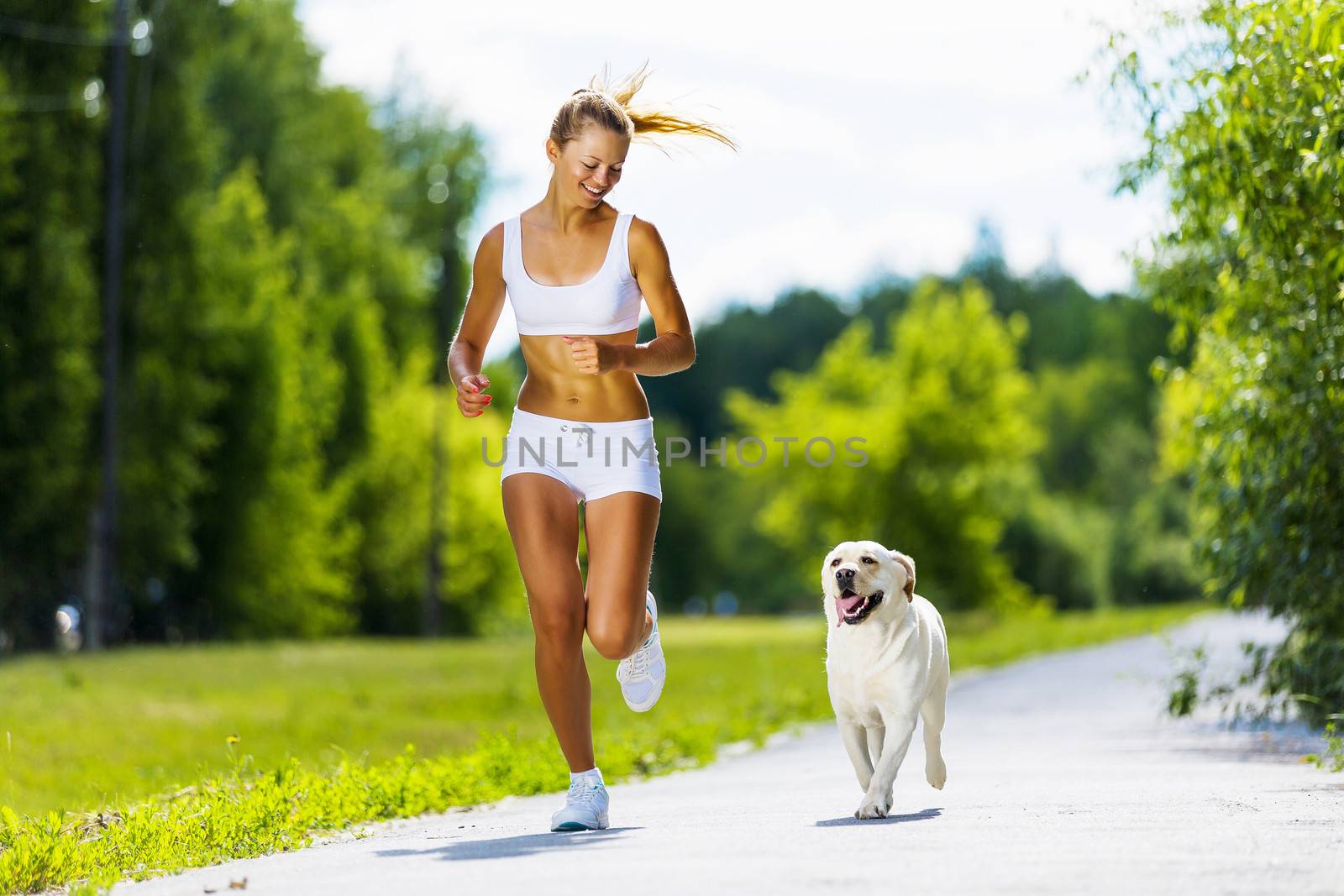 Young attractive sport girl running with dog in park