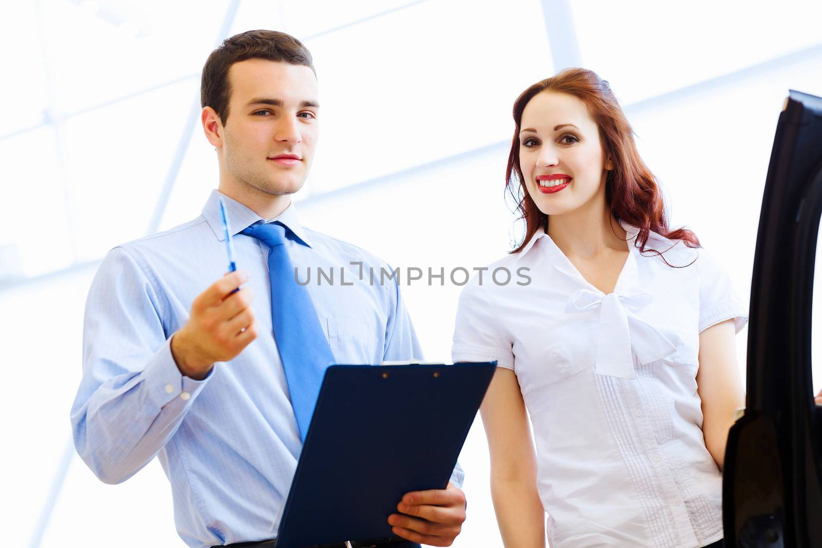 Attractive woman at car salon with consultant choosing a car