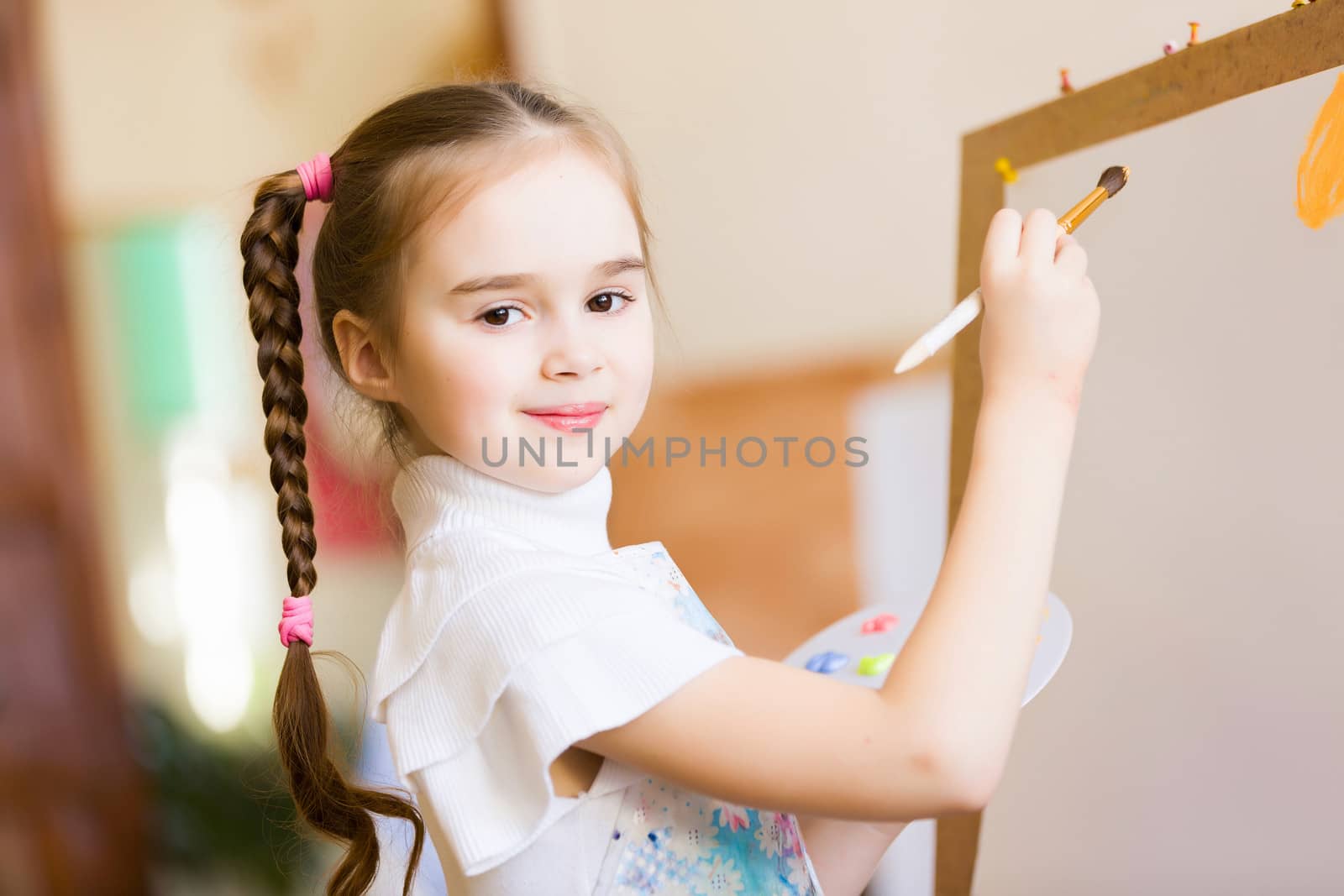 Little cute girl with paint brush and easel