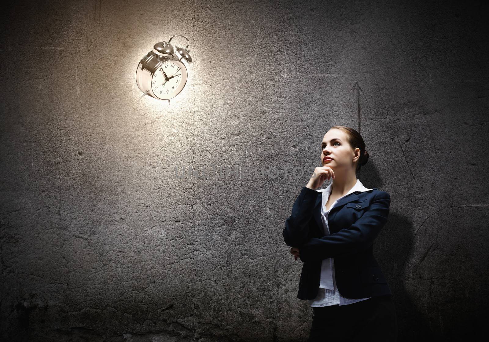 Image of concentrated businesswoman looking at alarm clock