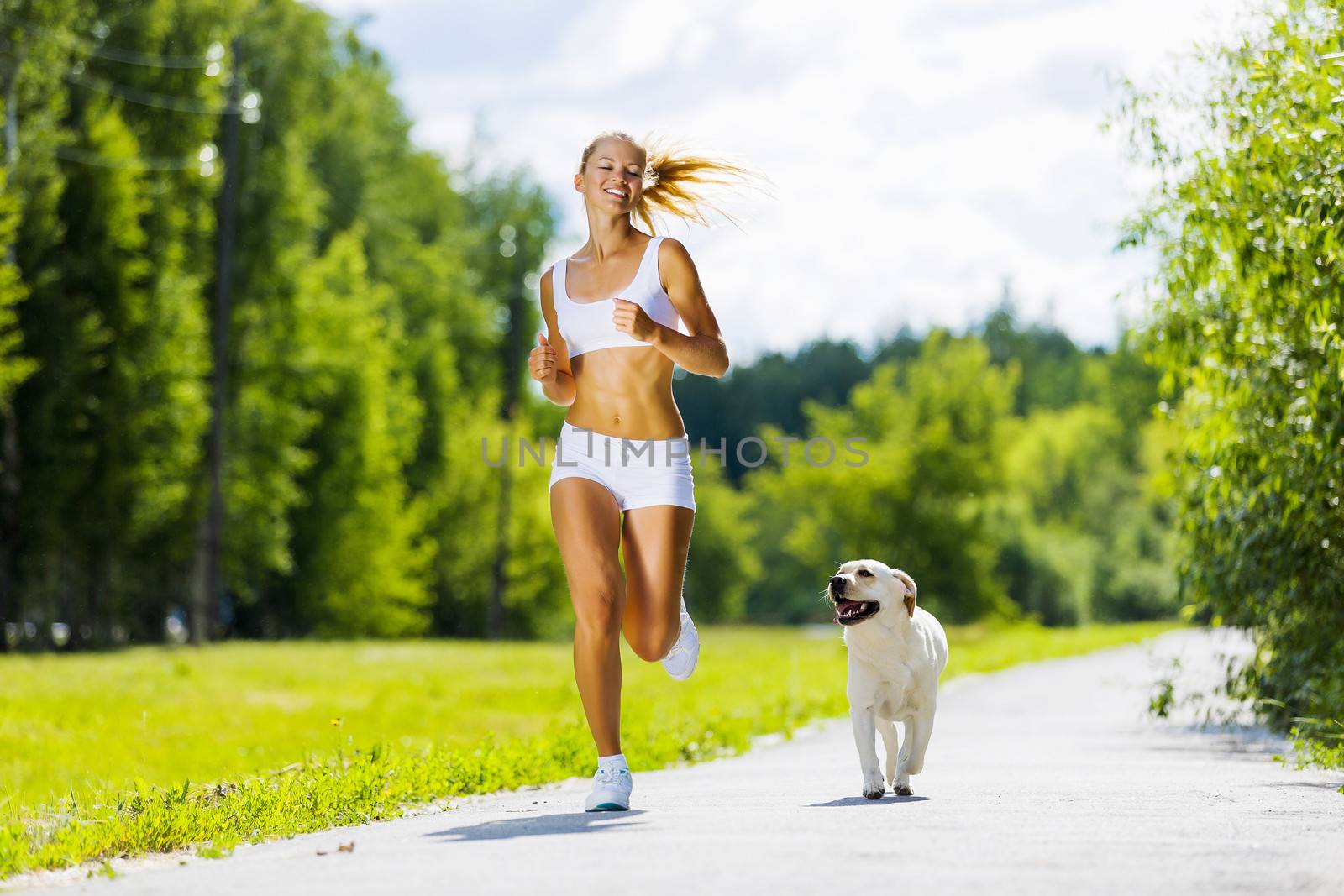 Young attractive sport girl running with dog in park