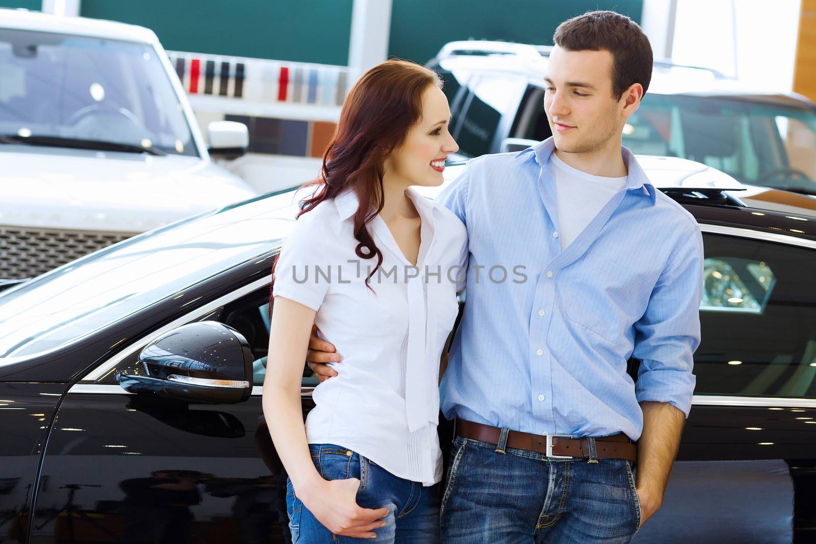 Two pretty young people smiling standing near car