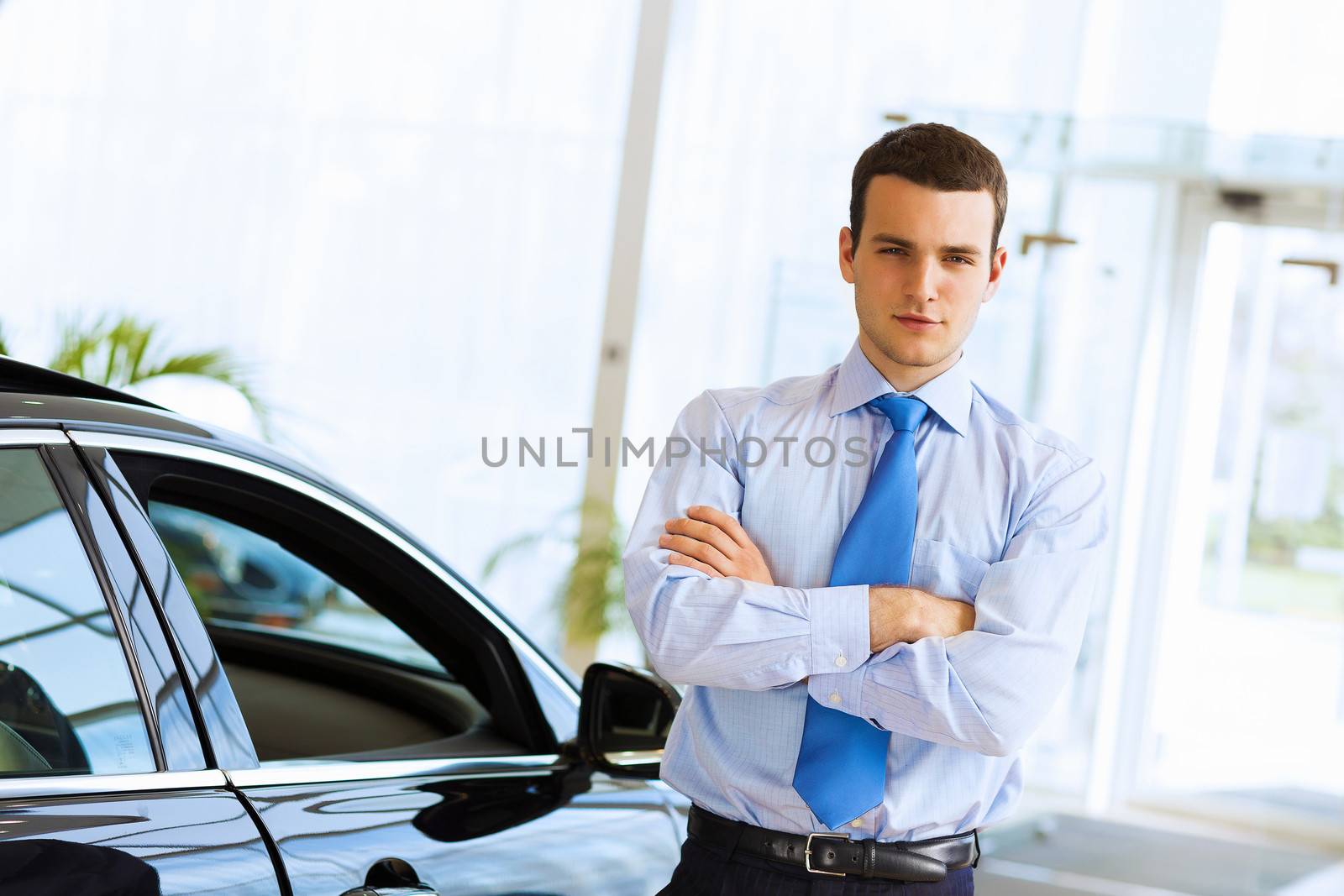 Image of handsome young businessman in suit standing near car