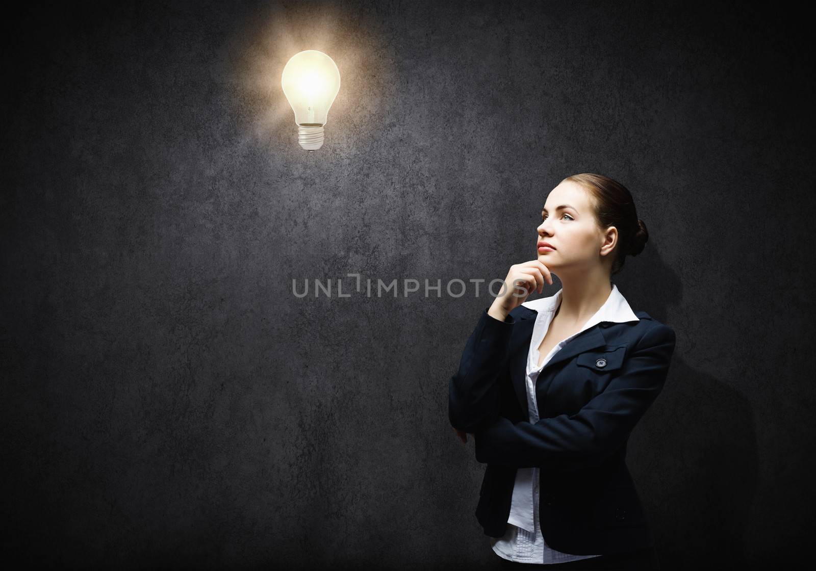 Image of thoughtful businesswoman looking at light bulb