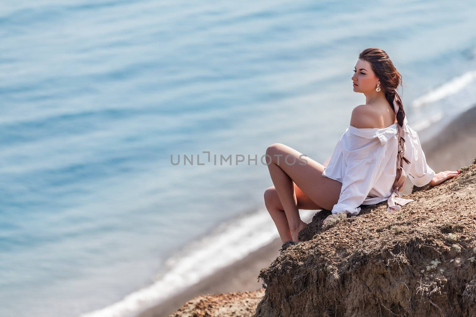 Girl sitting on a rock and looking at sea