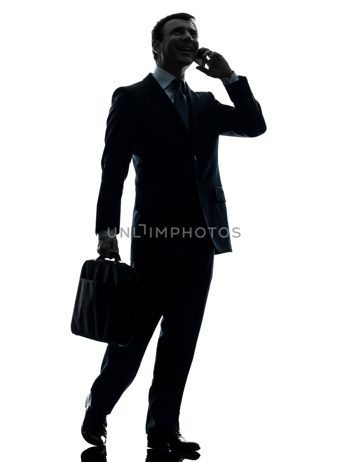 one caucasian businessman walking on the telephone in silhouette studio isolated on white background