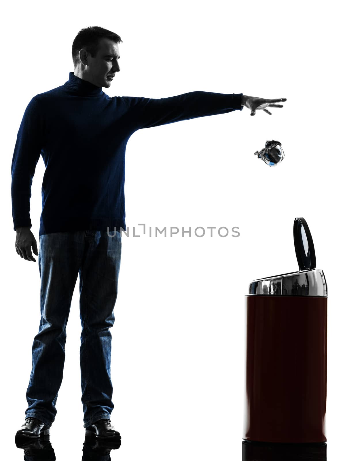 one caucasian man dropping a paper in a trash bin full length in silhouette studio isolated on white background