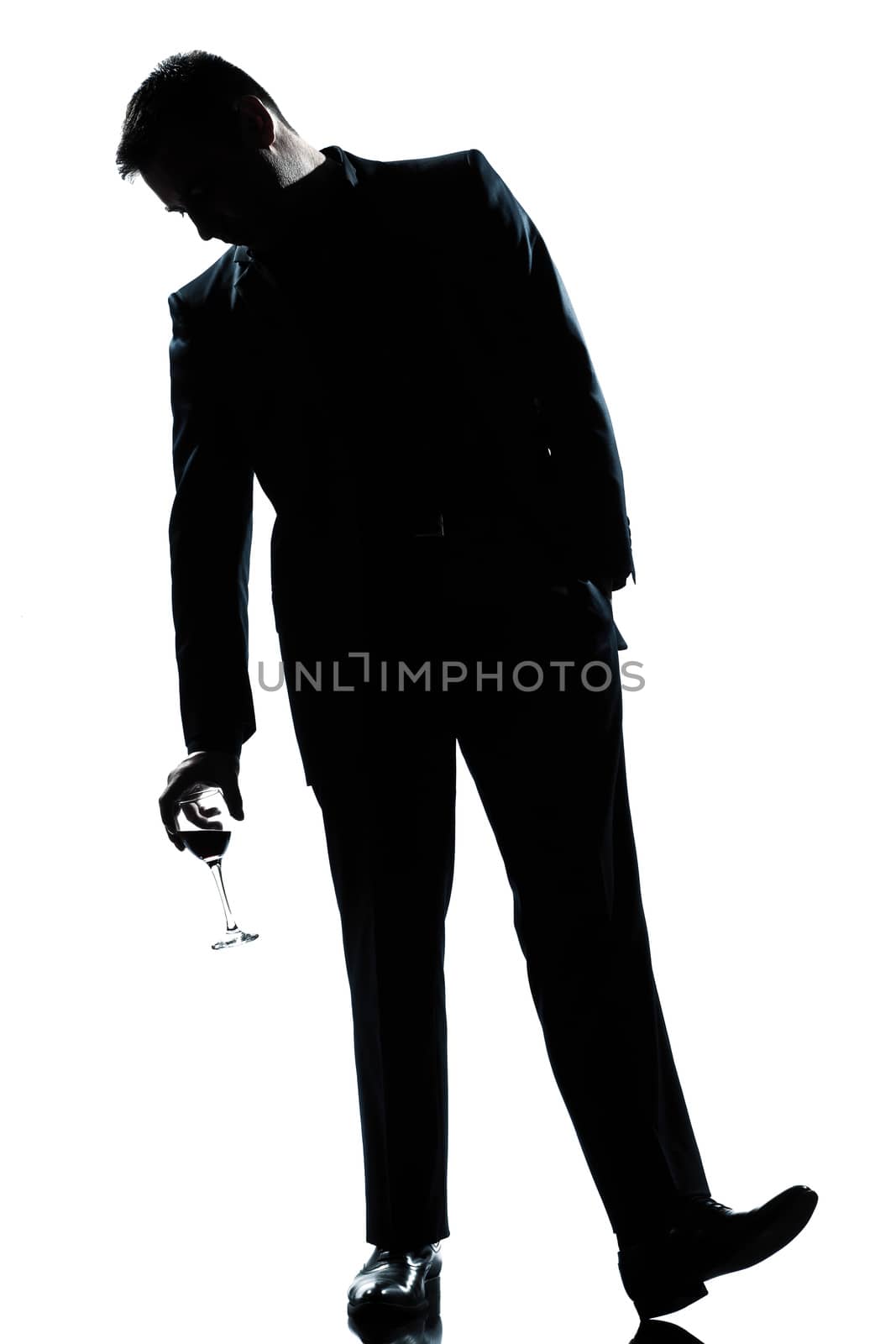 one caucasian man full length silhouette  drunk holding a glass of red wine in studio isolated white background