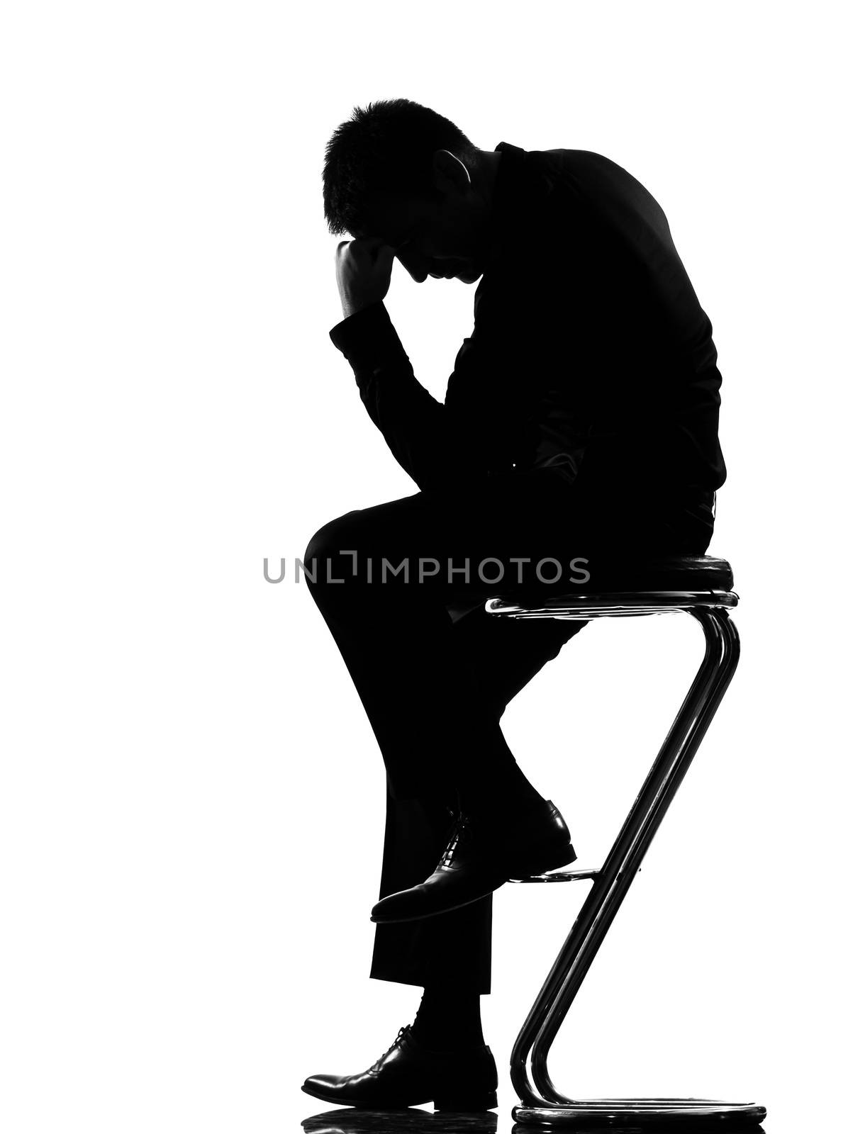 silhouette caucasian business man thinking pensive sititting on foot stool full length on studio isolated white background