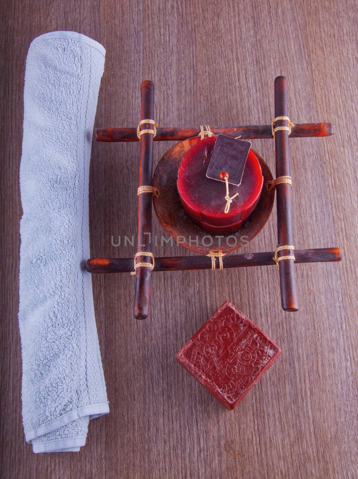 Brown soap, candle and towel over wooden background