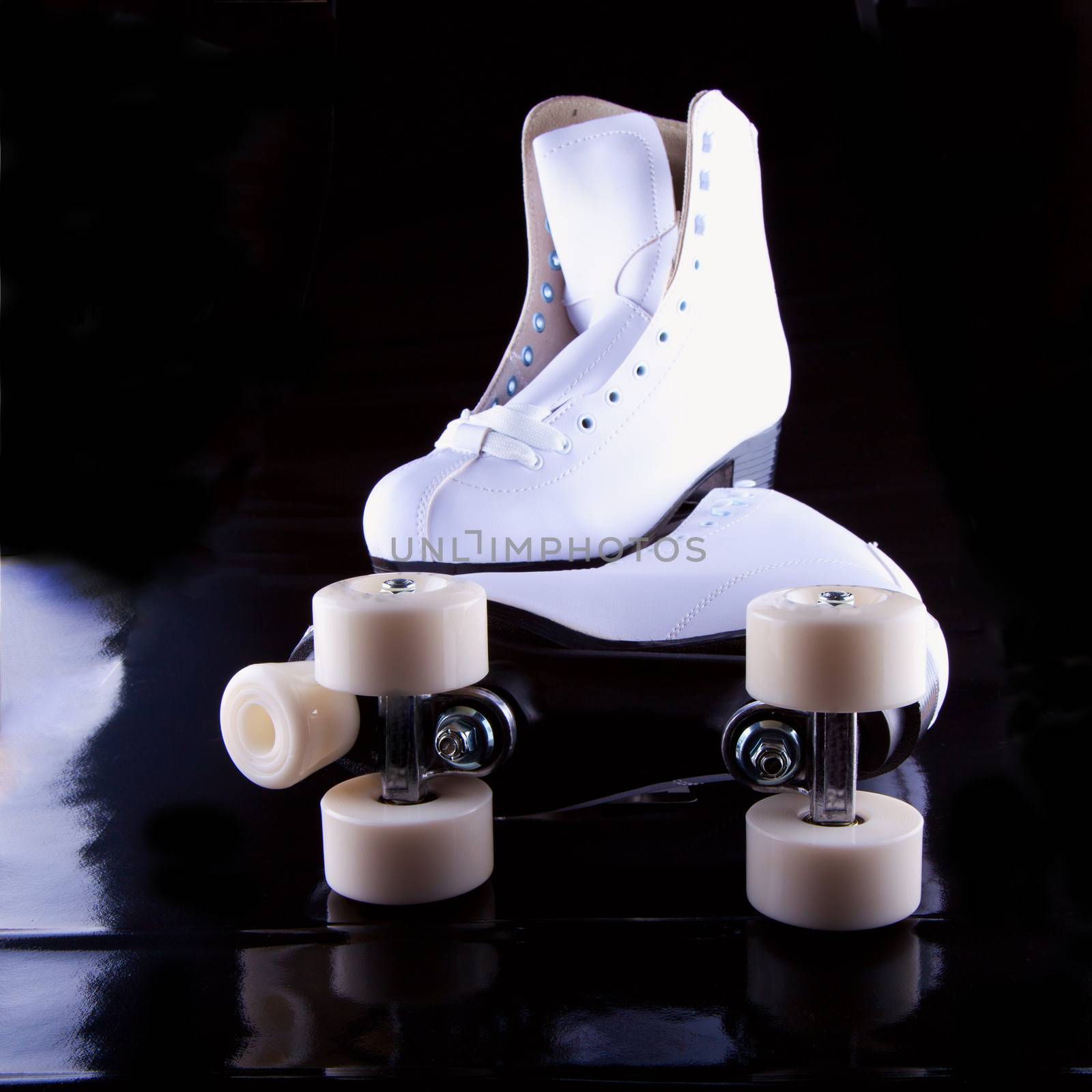 A pair of white roller skates over black background