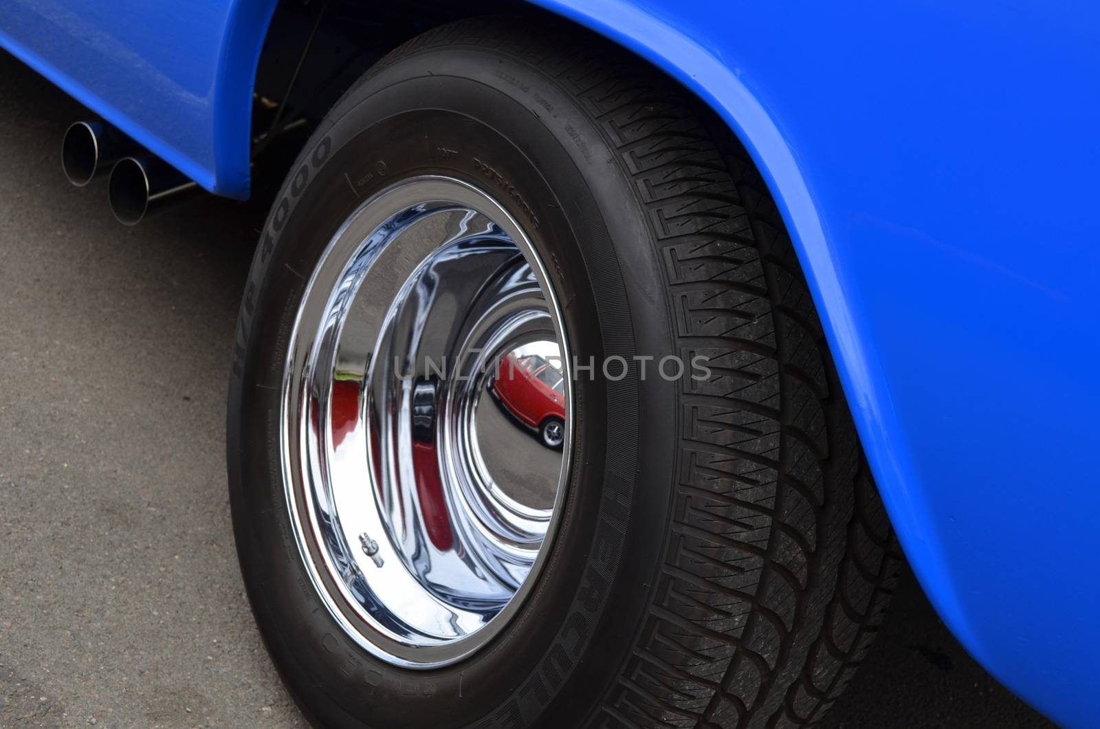 Rear wheel and tyre on a custom car showing chrome and bright paint work.