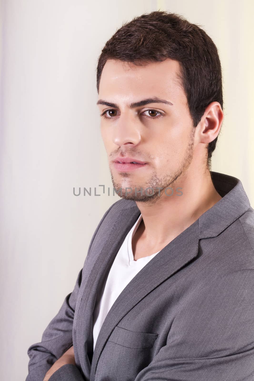 View of a young man standing against a white  background. 