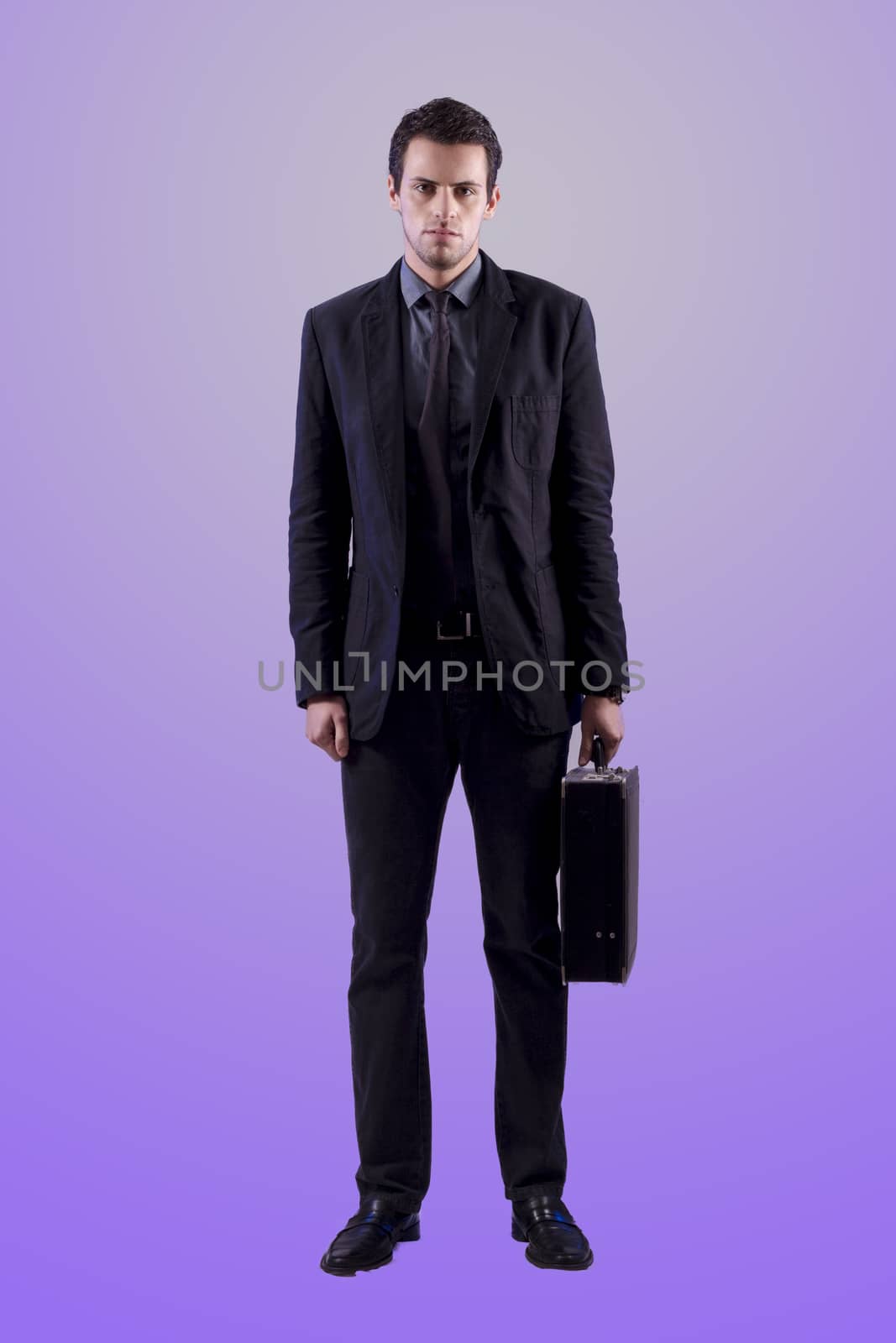 View of a young business man standing against a grey  background. 