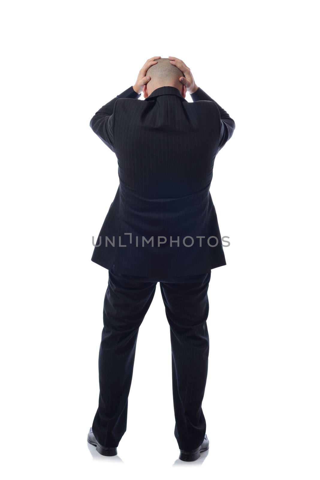 business man in modern elegant suit standing back holding head with his hands, isolated over white background. Concept of neck or head ache, pain, problem, tired up. 