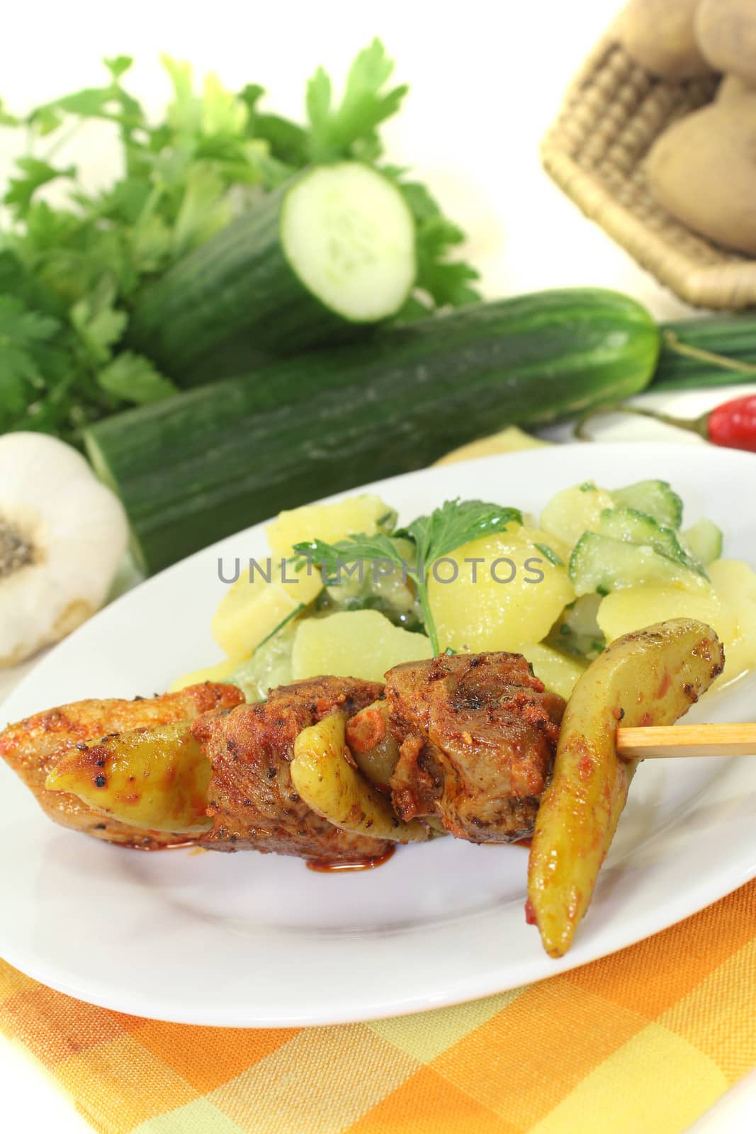 Potato-cucumber salad with fire skewers and chilli on a light background