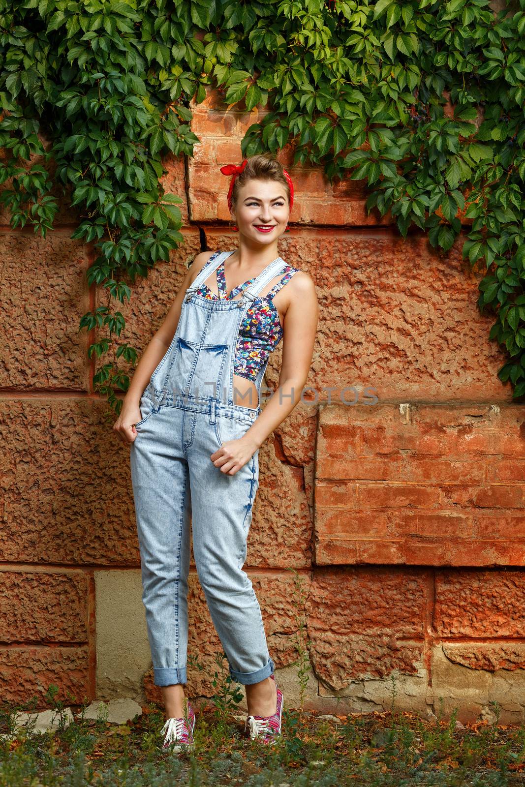 Beautiful pin-up girl in denim overalls and a T-shirt outdoors