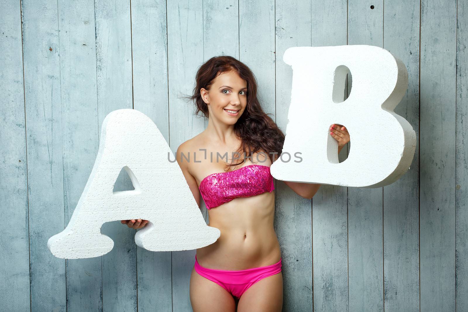 Beautiful girl in a bathing suit holds in hands letters