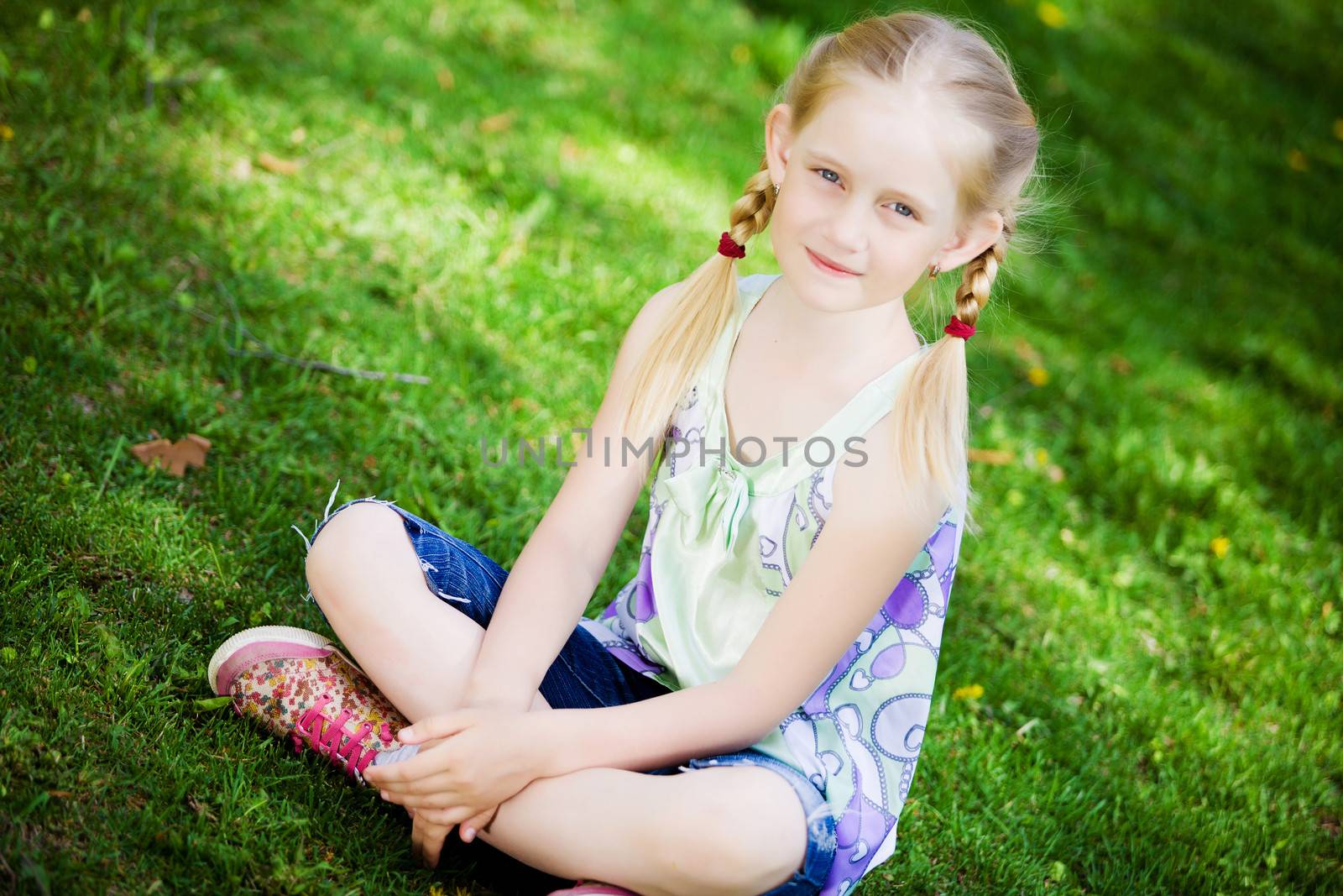 Image of little cute girl sitting on grass in park