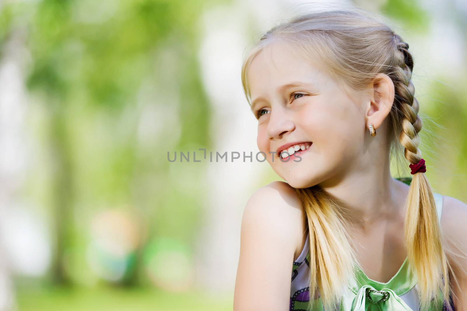 Image of little cute girl sitting on grass in park