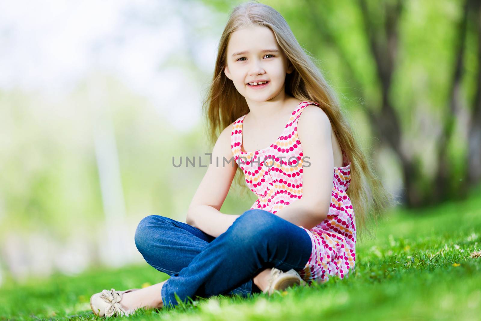 Image of little cute girl sitting on grass in park