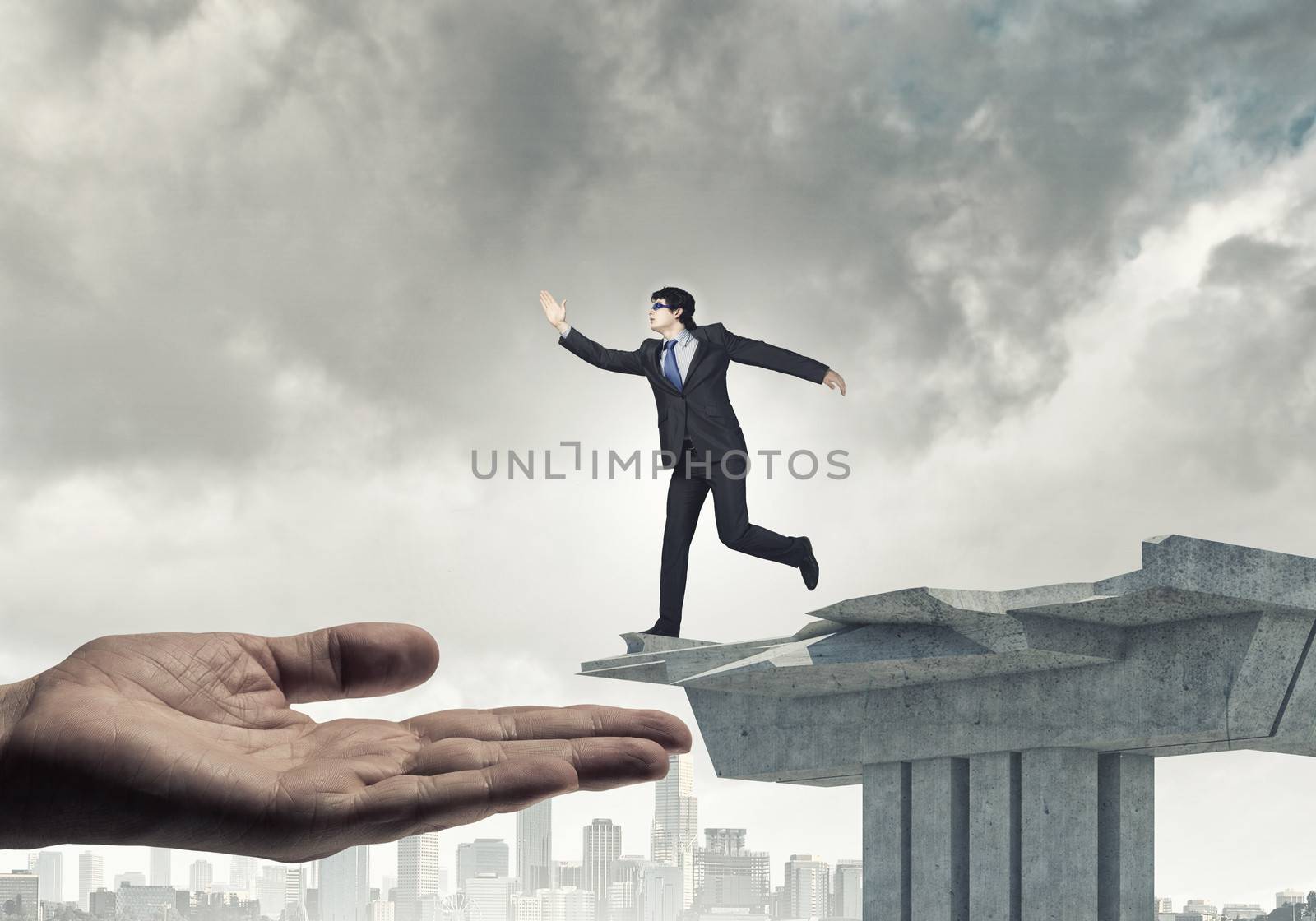 Image of running businessman at the edge of bridge supported by human hand